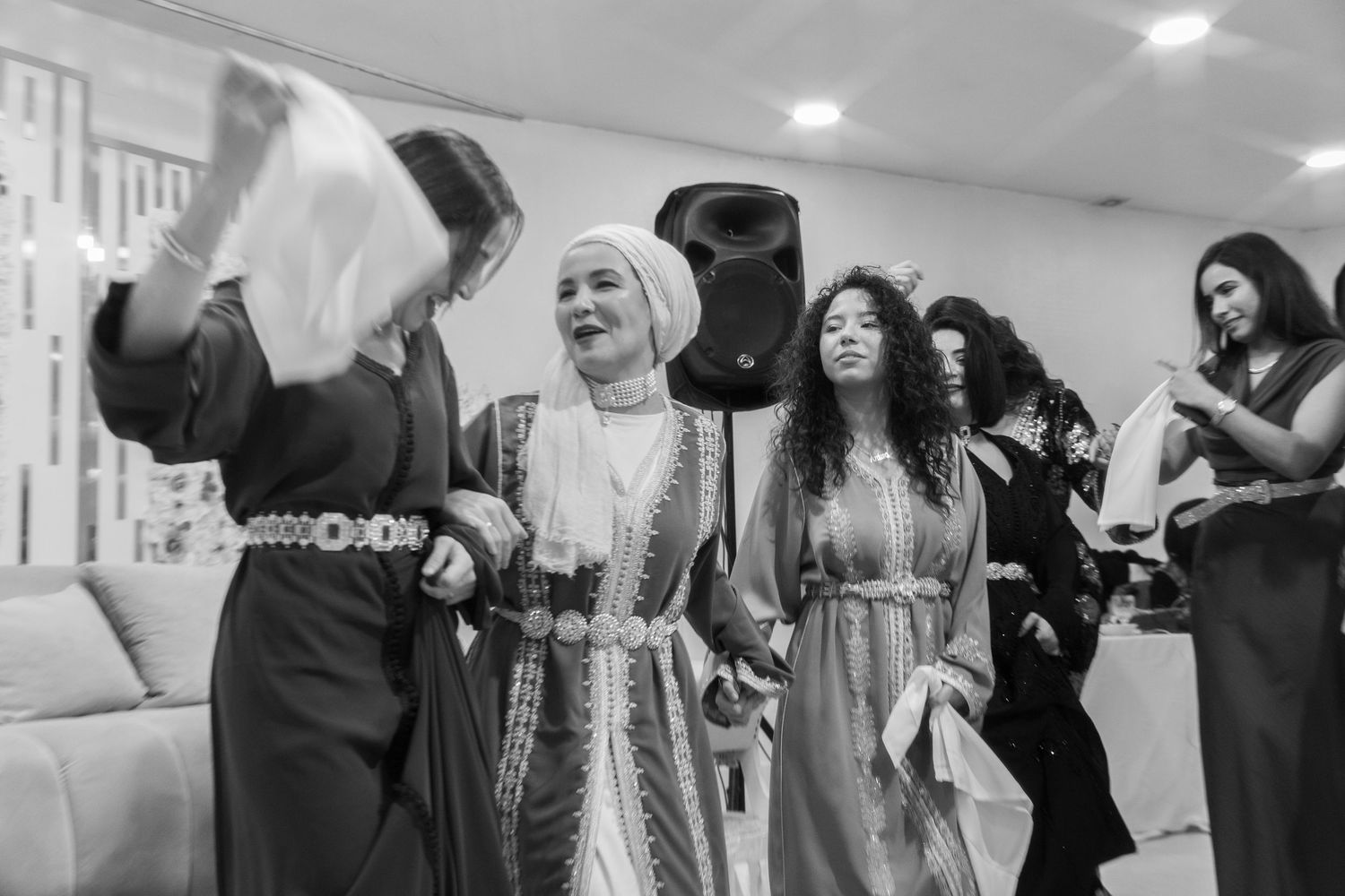 Women in traditional embroidered dresses dancing and celebrating joyfully at a cultural event.