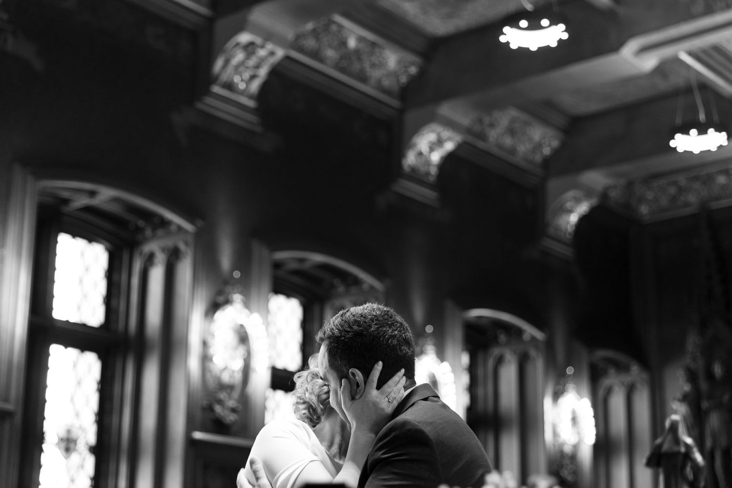 Black and white photo of a couple sharing a first kiss in an ornate wedding venue. photography brussels