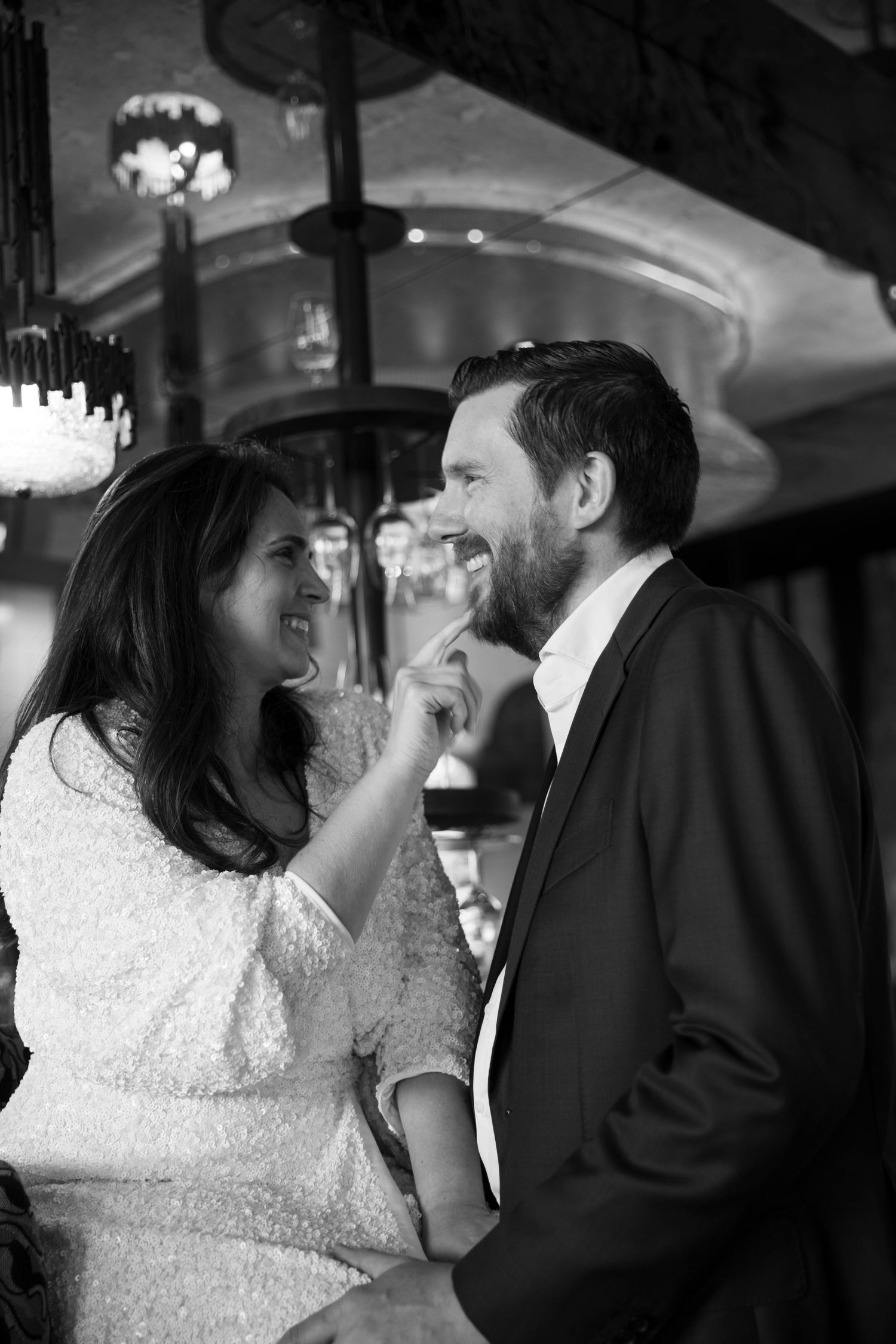 Black and white photo of a smiling couple sharing a tender moment at an elegant venue.
