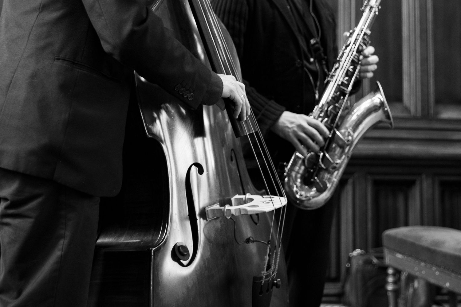 Black and white photo of musicians playing upright bass and saxophone at a jazz performance.