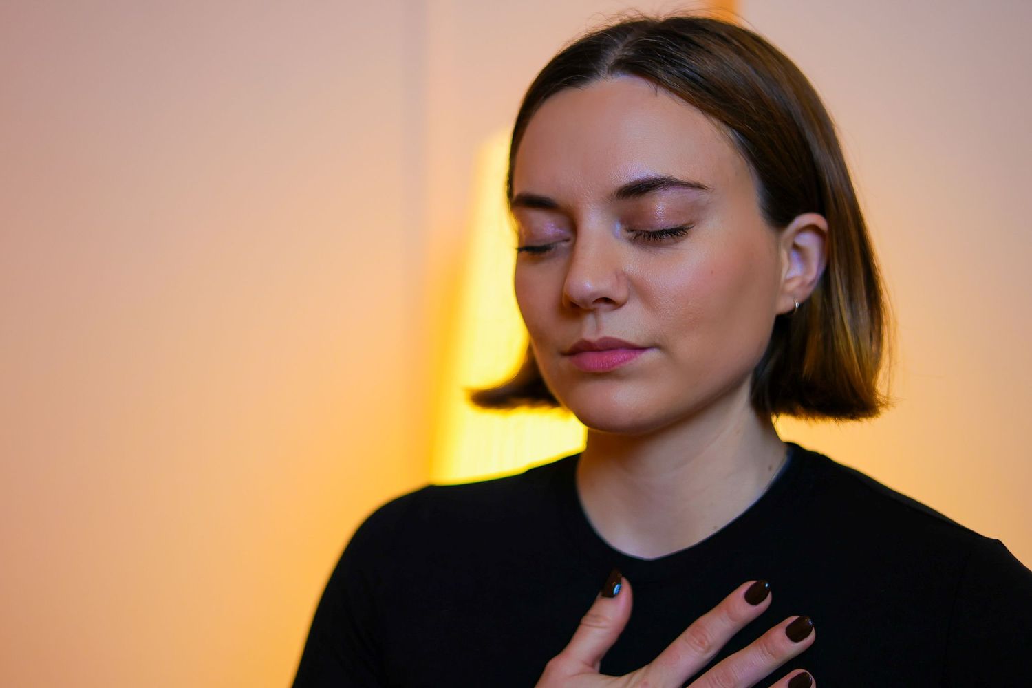 A series of portrait photos showing a person with closed eyes in warm lighting against a soft pink background.