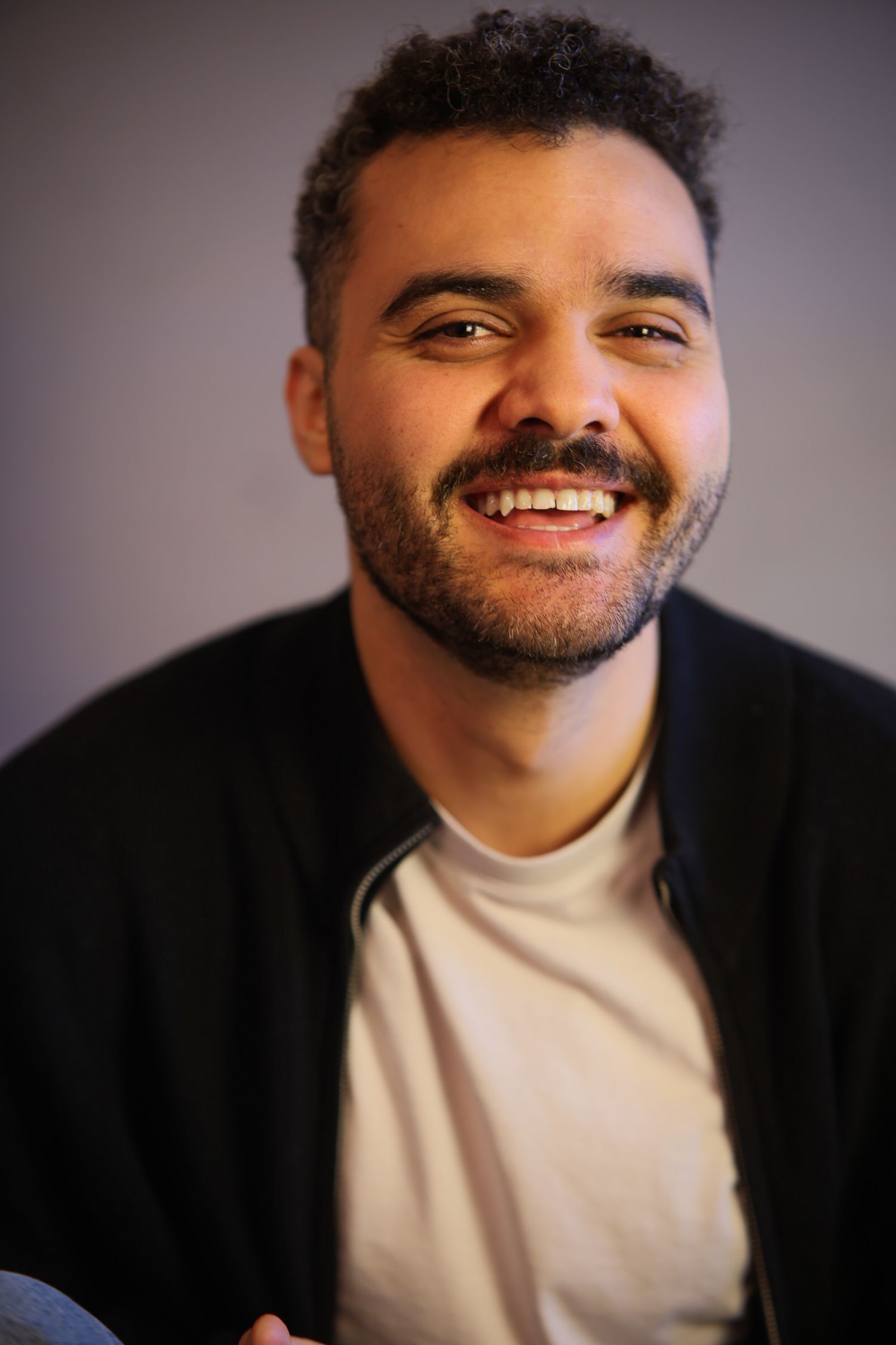 A series of headshots showing expressions progressing from neutral to joyful in a white turtleneck against a dark background.