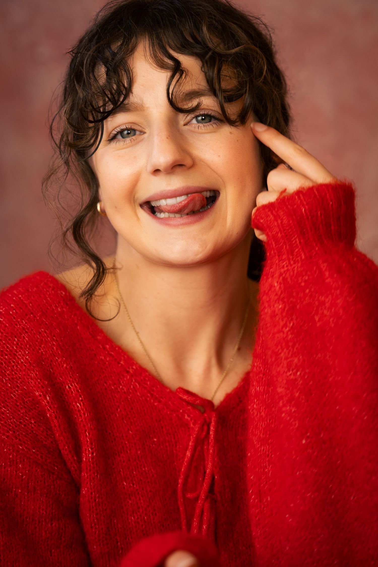 Portrait series showing joyful expressions and a cozy red sweater against a warm burgundy background.