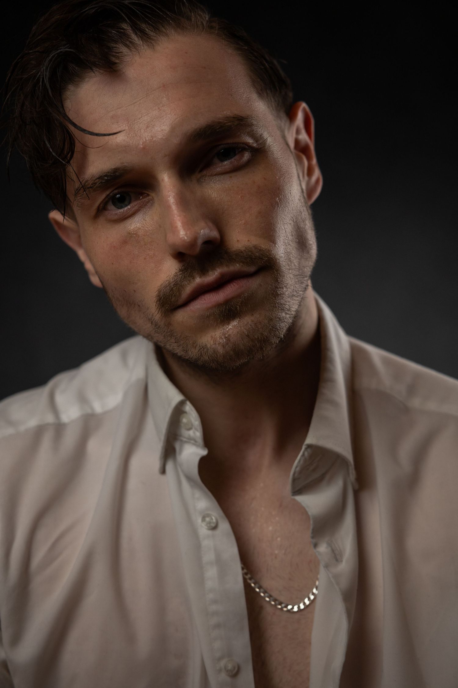A series of moody portrait photos showing a person in a white button-down shirt against a dark background.