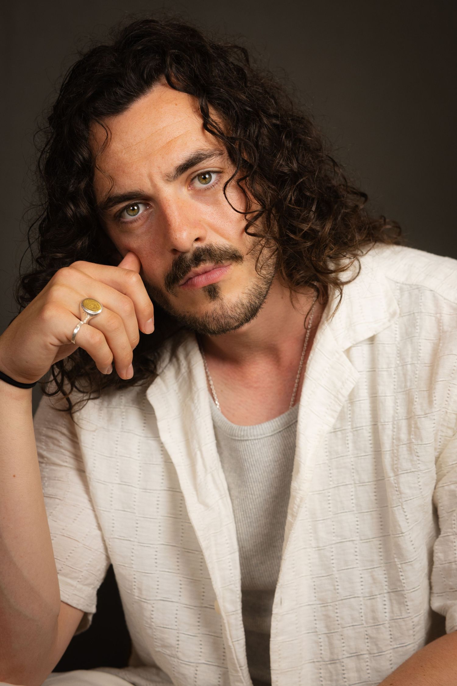 Portrait series showing a person with curly dark hair wearing a white shirt in various contemplative poses.