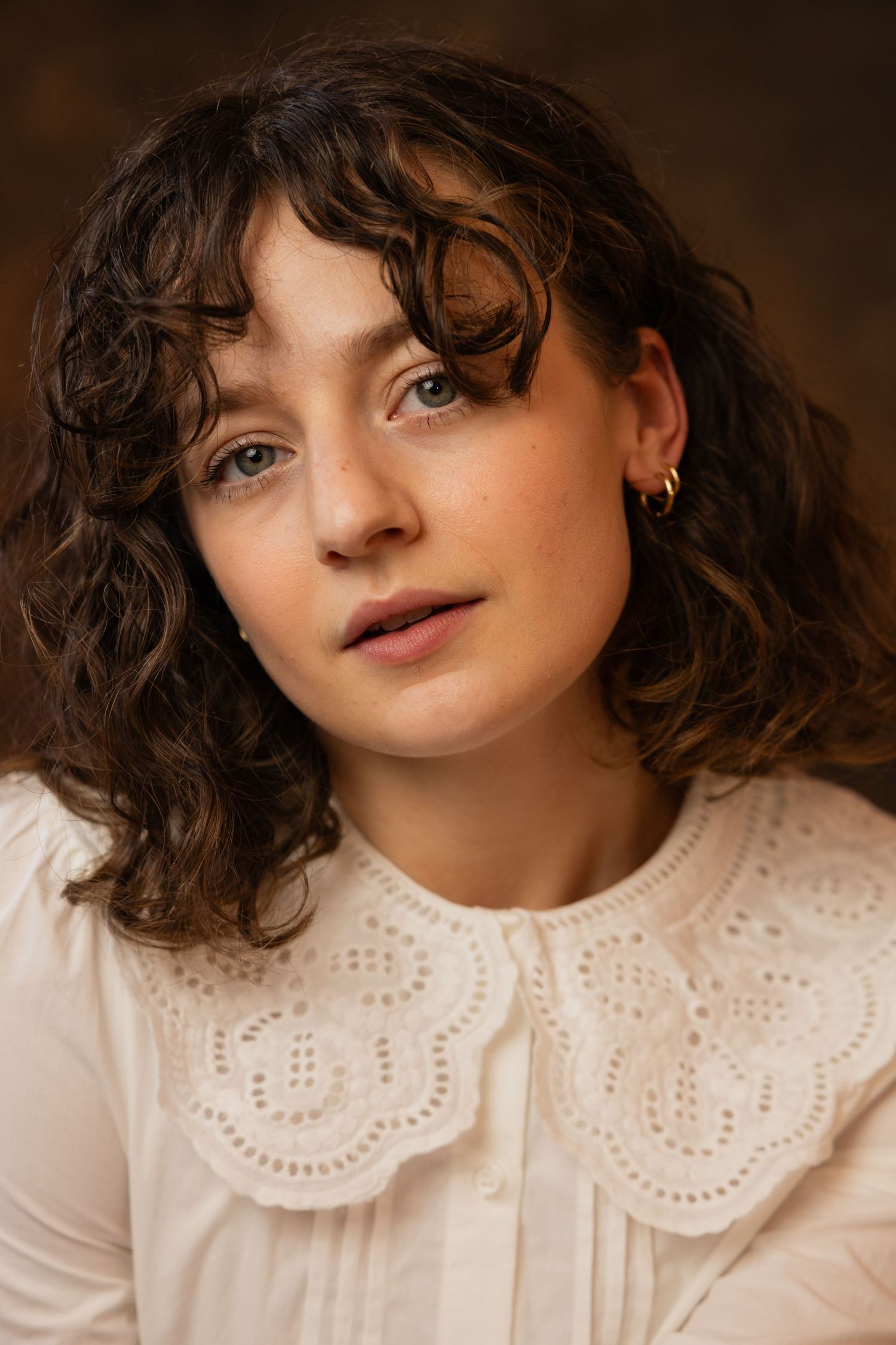 Portrait series showing a vintage-inspired look with a white lace peter pan collar and natural curly hair in warm lighting.
