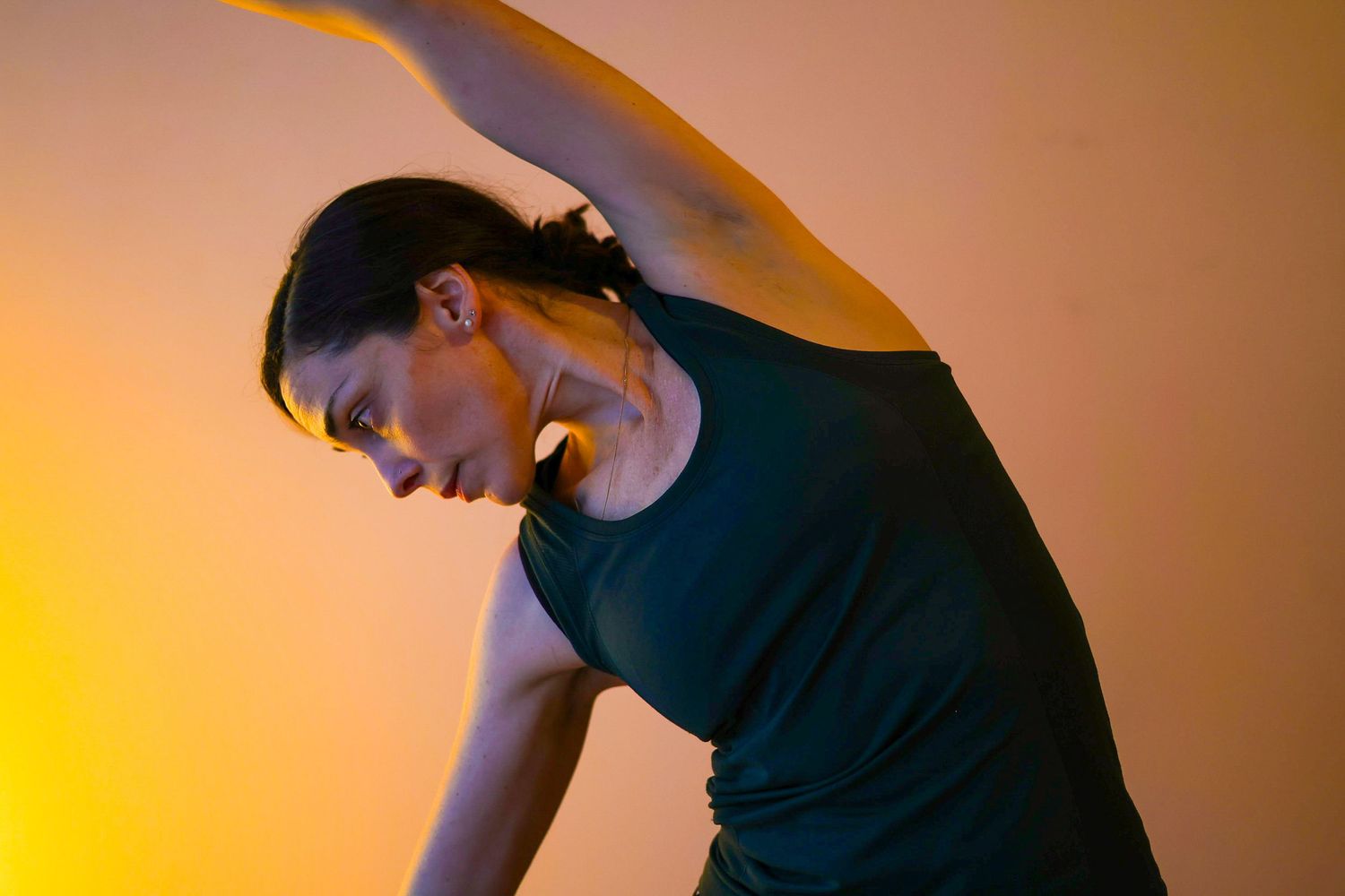 A person in a black t-shirt stands against an orange-lit wall creating dramatic silhouettes and shadows.
