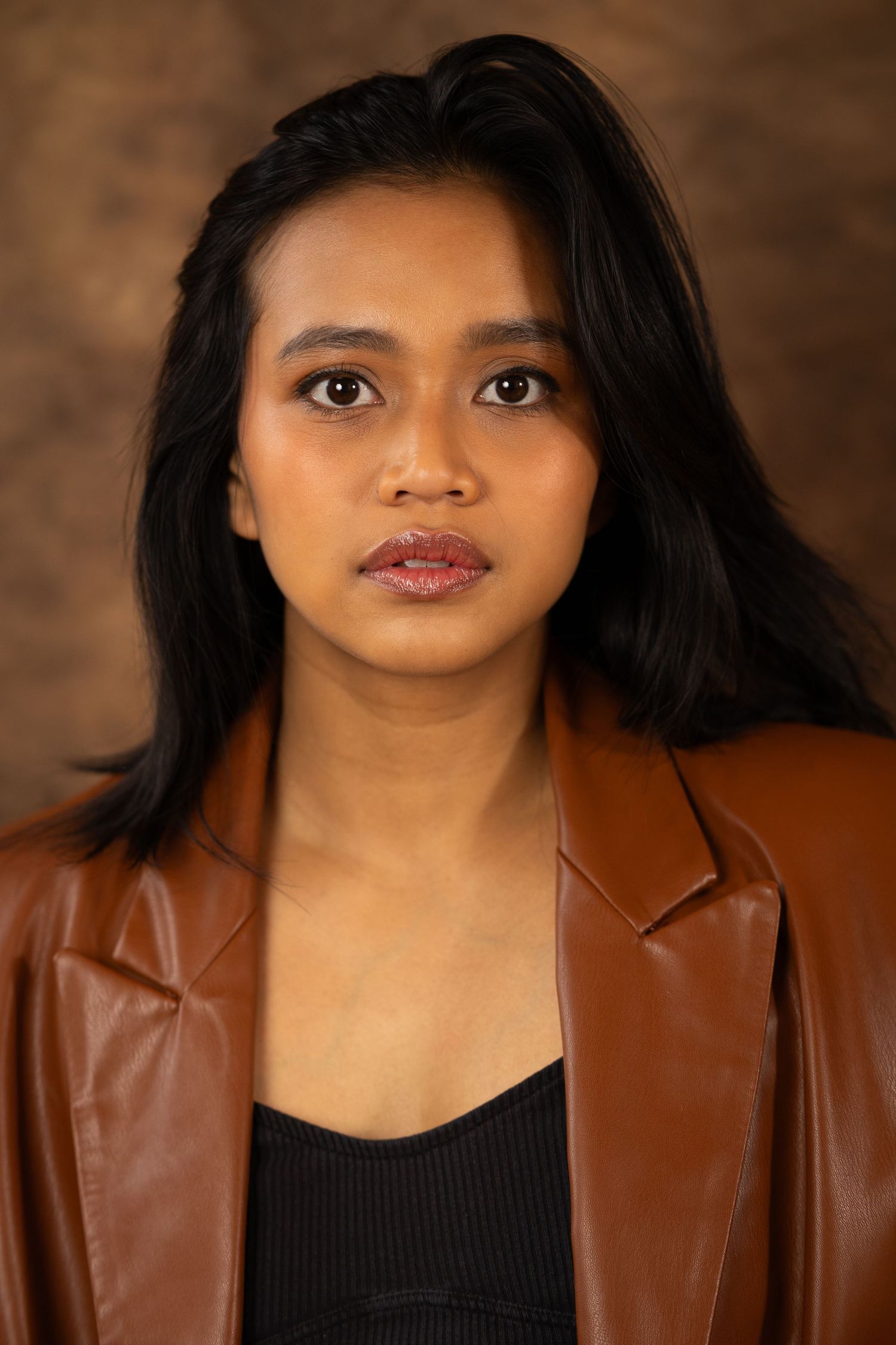 A series of five close-up portrait photos showing expressions while wearing a brown leather jacket and black top.