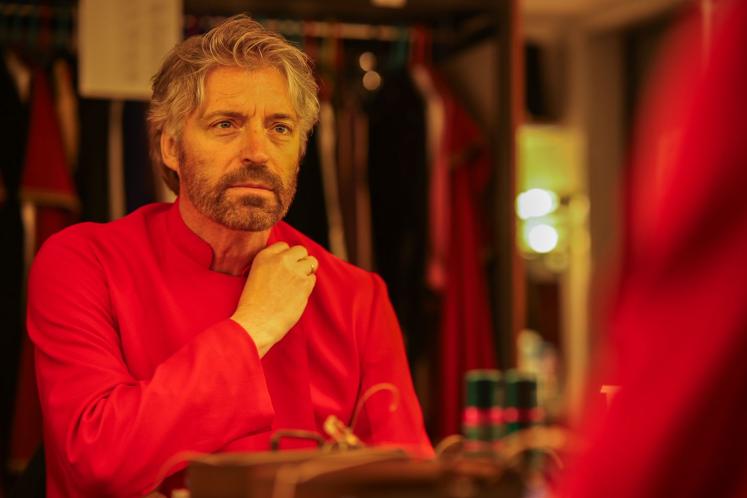 Person wearing a bright red sweater seated at a dimly lit restaurant or bar setting.