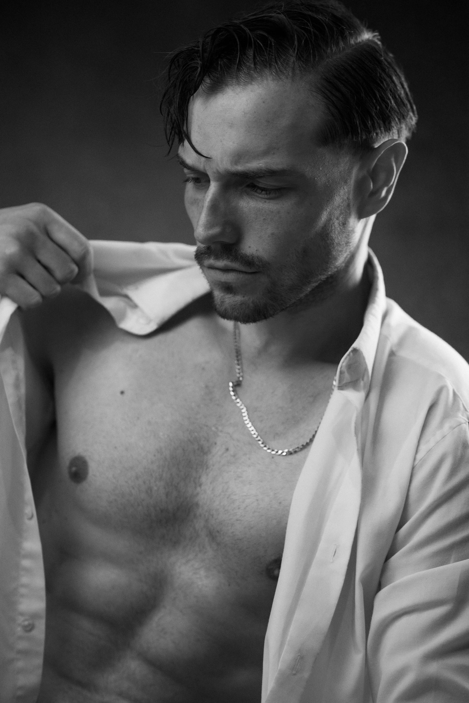Black and white artistic portrait series showing a person in a white shirt against dark background.