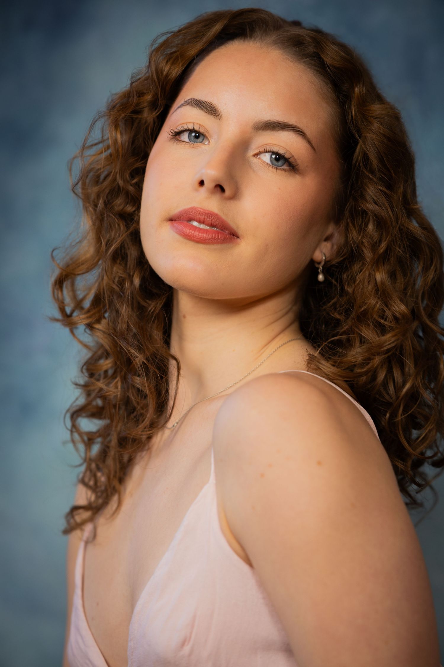 Portrait series showing a woman with curly brown hair and pink lipstick posing against a blue backdrop.