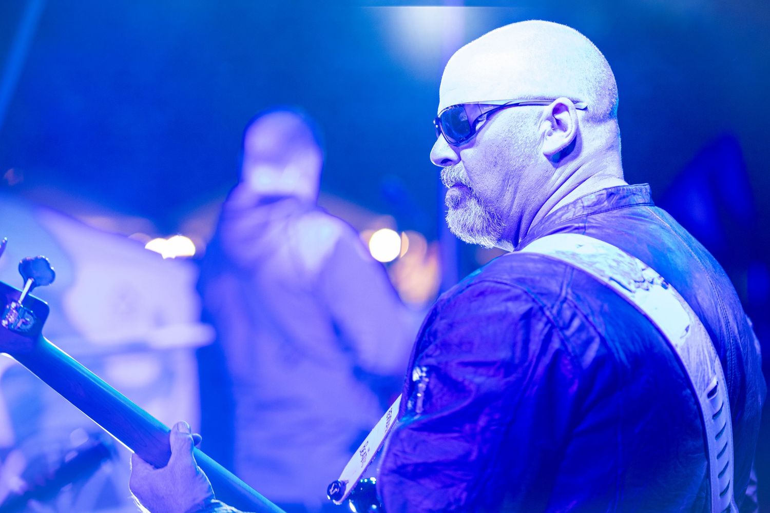 Musicians perform on stage under dramatic blue lighting during a concert performance.