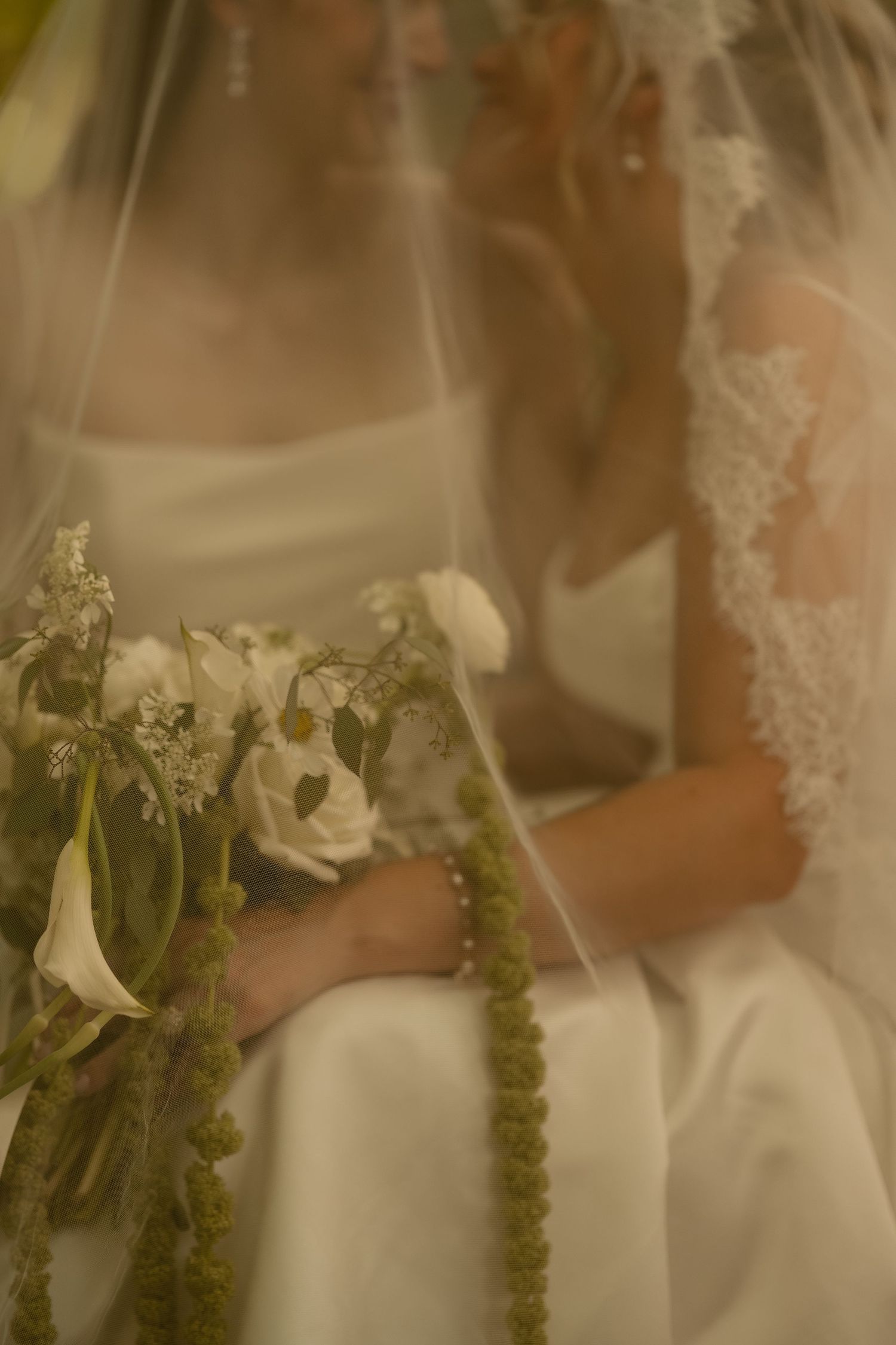 Delicate white floral bouquets adorned with sage green stems and foliage against a soft blurred background.