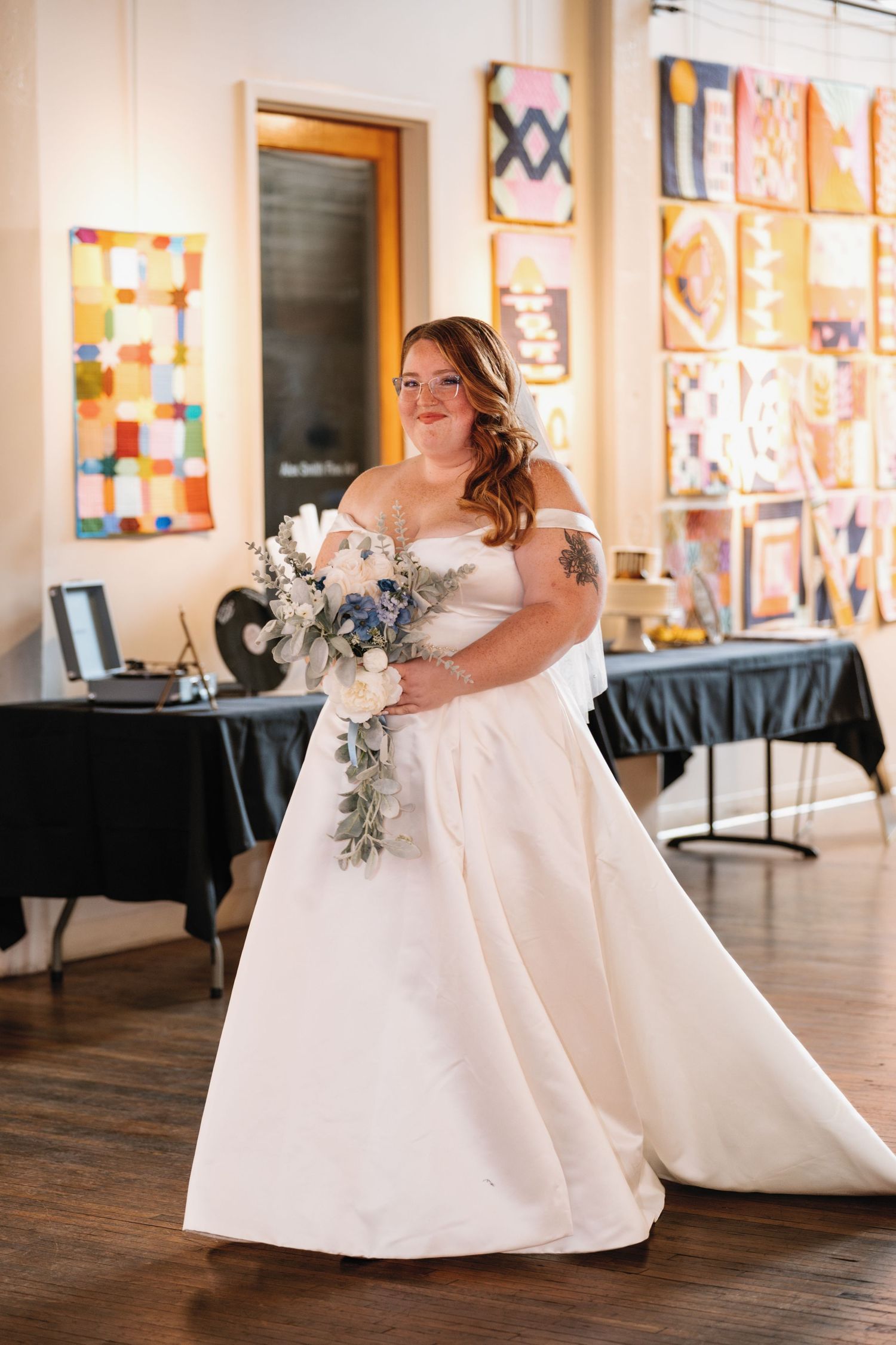A bride in a classic white ballgown poses elegantly in an art gallery with colorful artwork displayed on the walls.