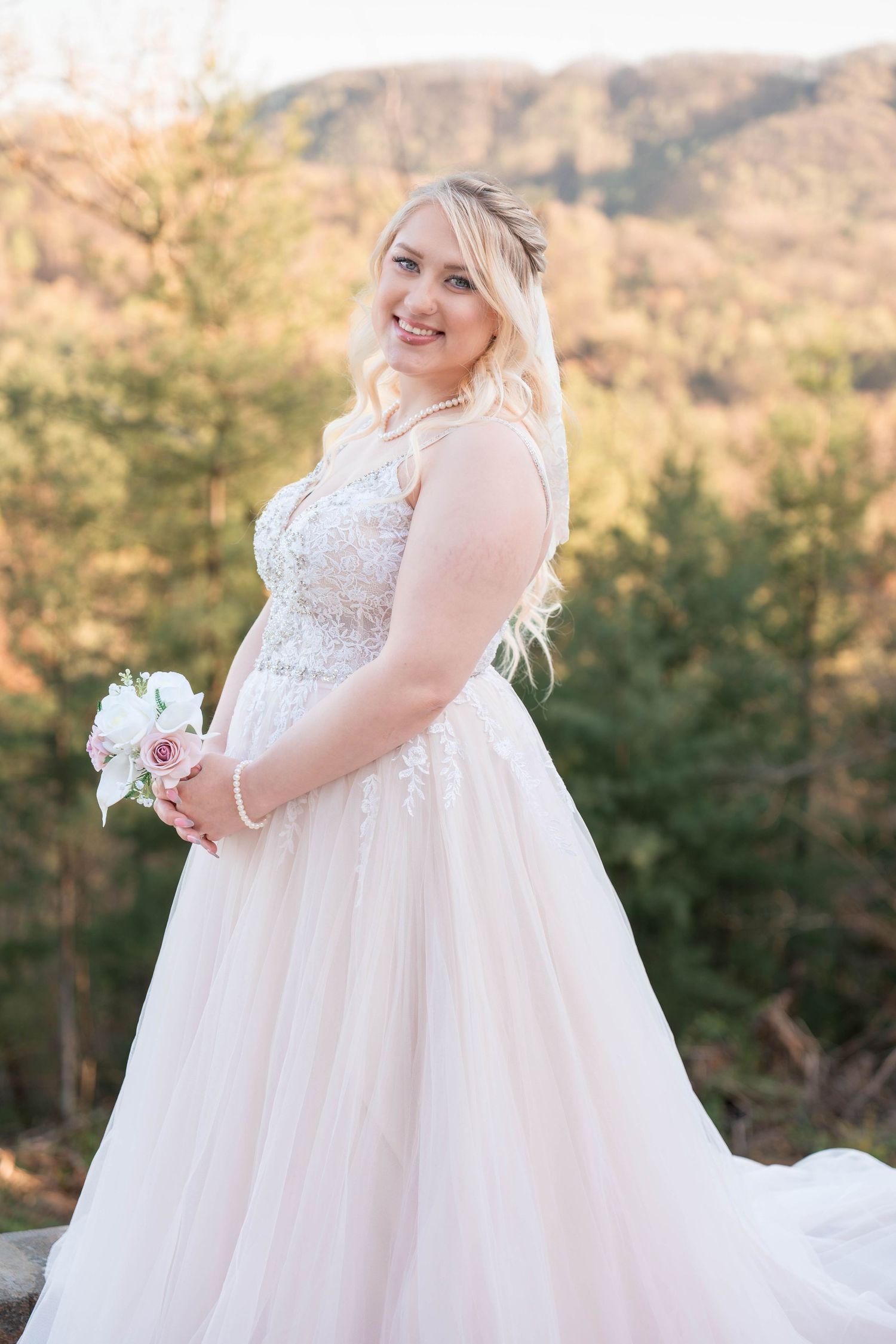 A plus size wedding gown with delicate lace bodice and flowing tulle skirt is showcased in golden hour sunlight.