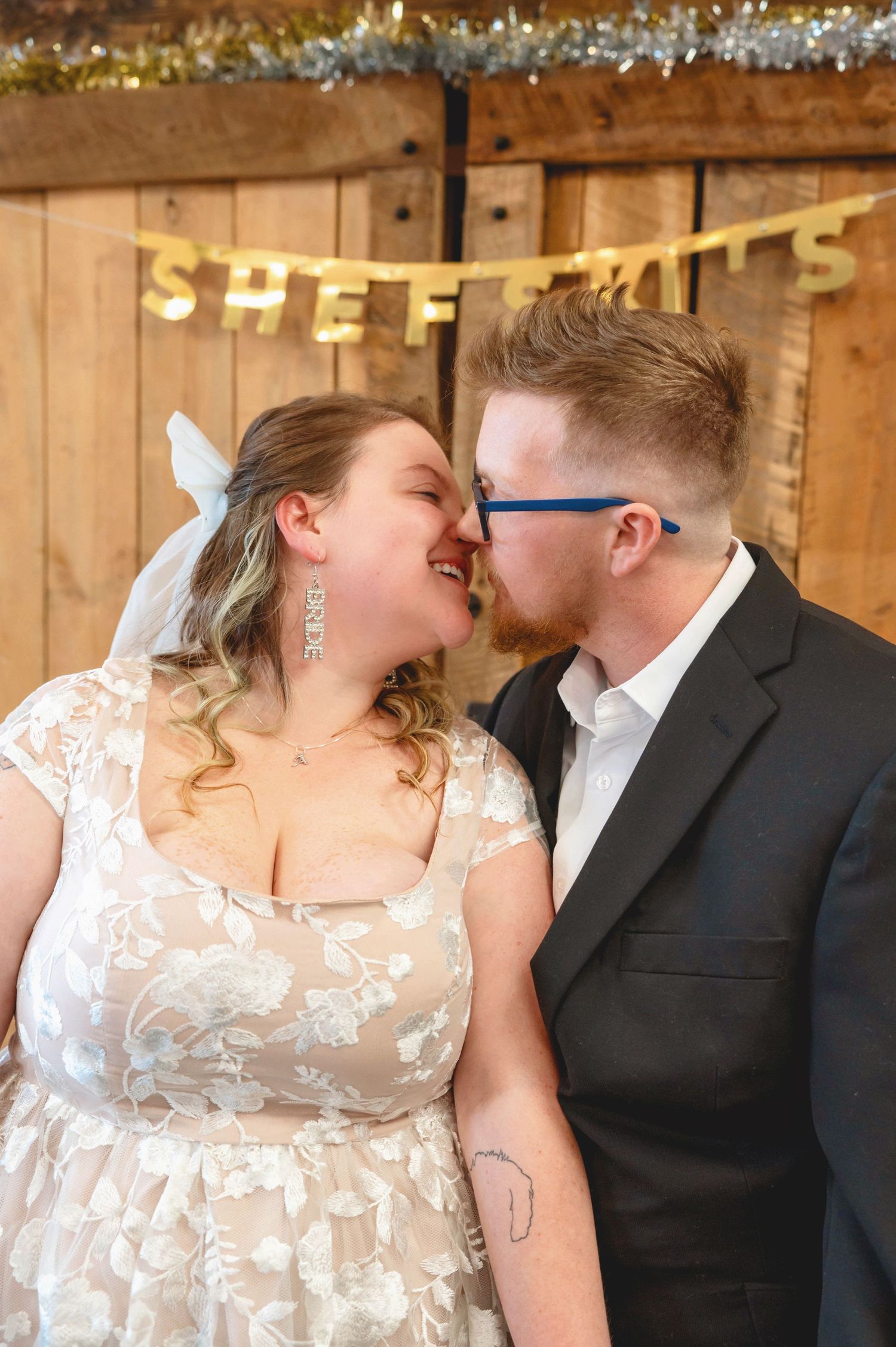 A romantic moment captured in a rustic venue with wooden walls and twinkle lights.