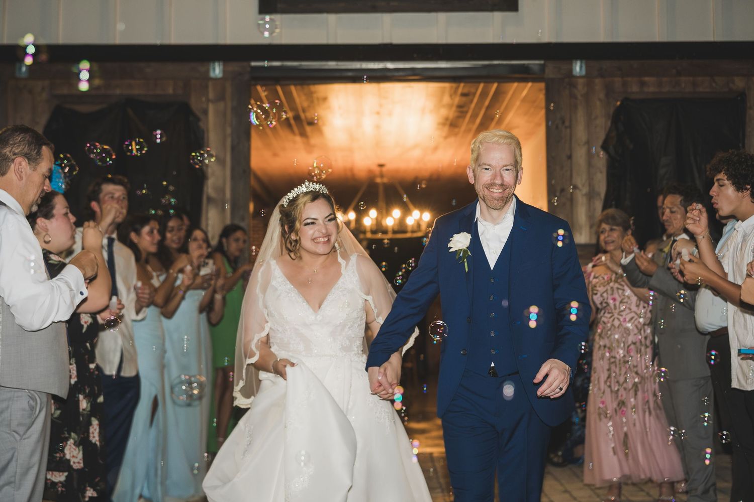 Wedding couple and guests dance together during a joyful reception celebration in an elegant indoor venue.