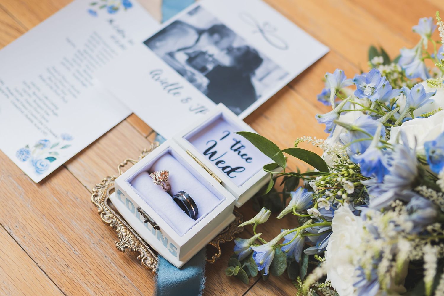 Wedding photos and cards displayed on wooden table with blue and white floral arrangements.