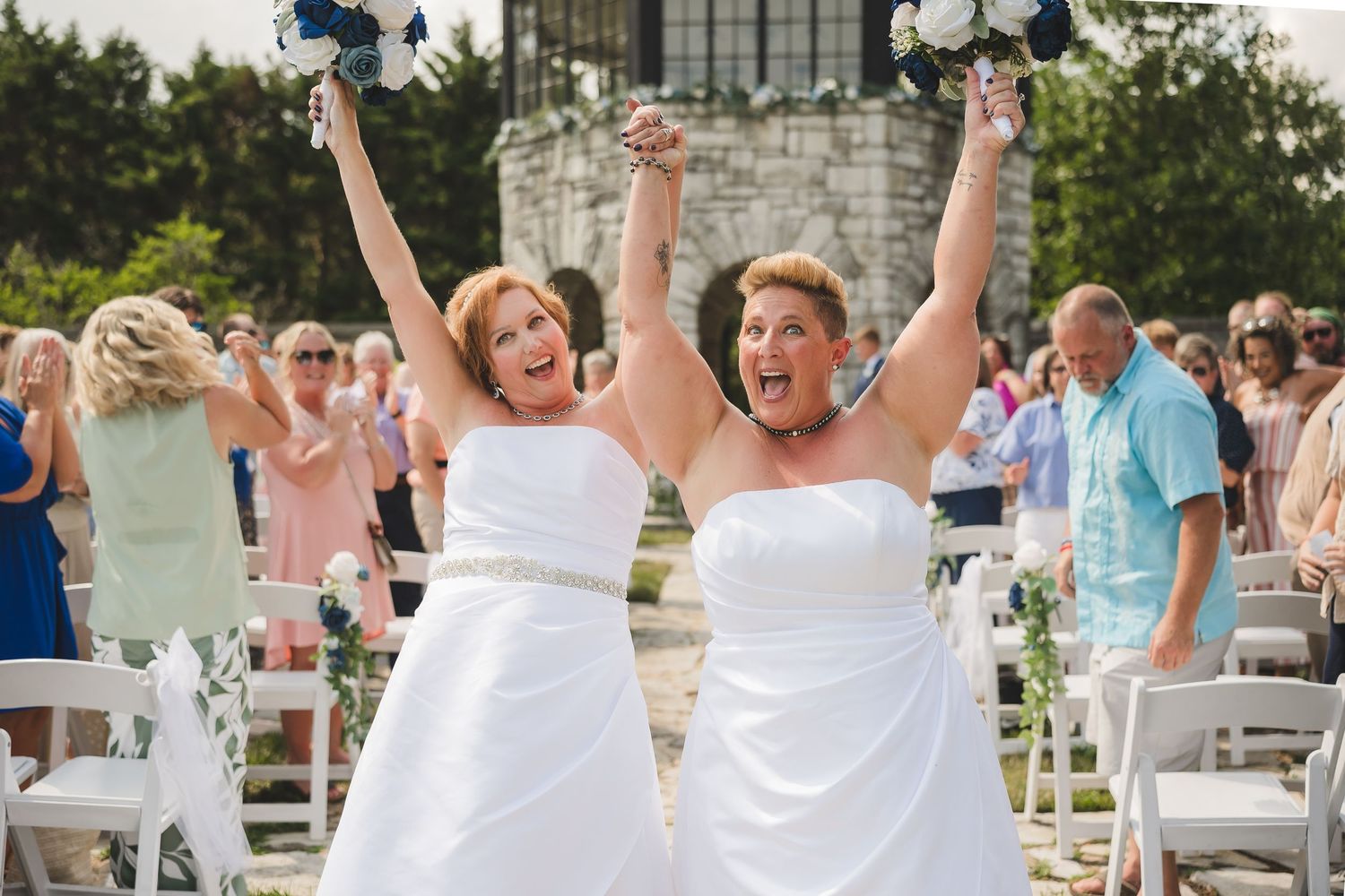 Joyful group of guests wearing all-white outfits celebrate outdoors at an elegant summer party or gathering.