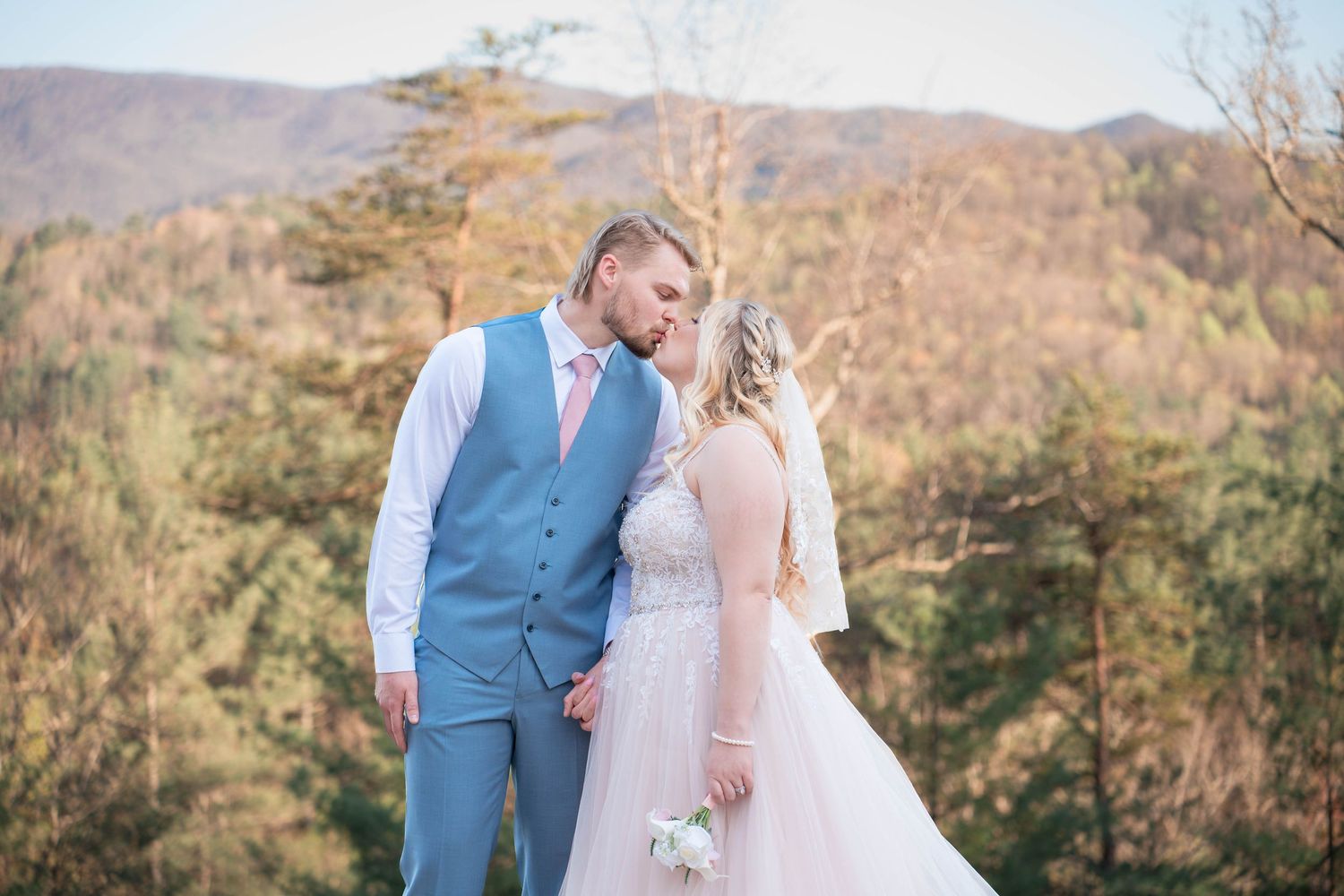 A couple shares an intimate moment at their mountain wedding ceremony during golden hour.
