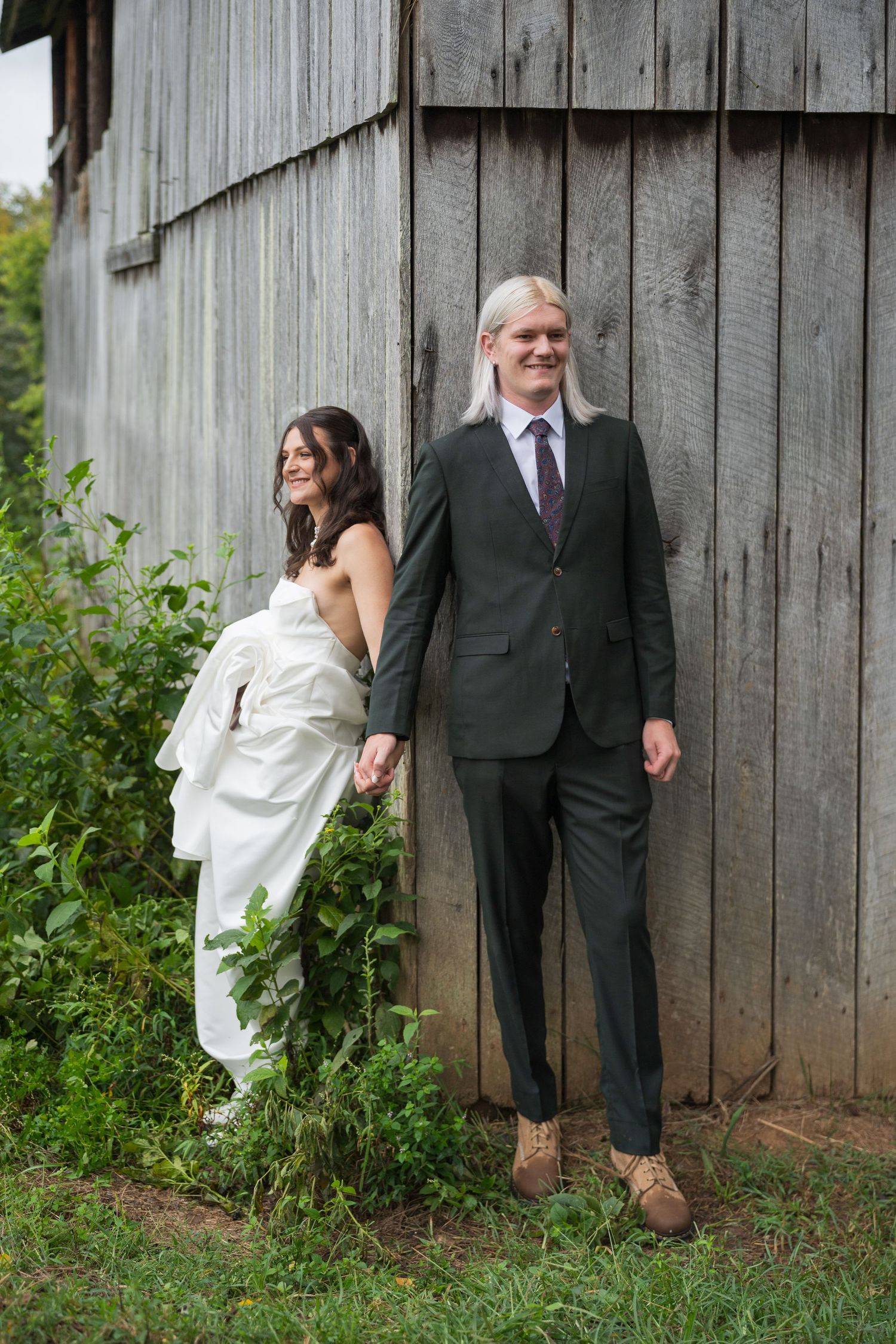 Wedding couple poses playfully behind rustic wooden barn wall in series of candid shots.