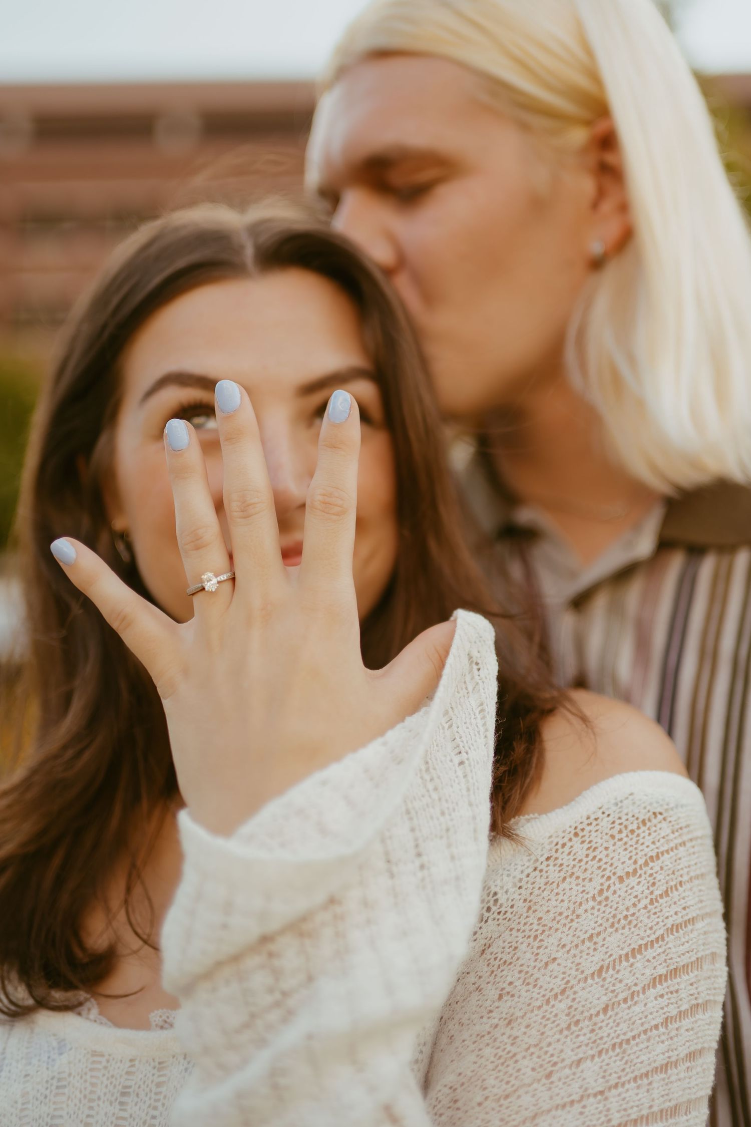 Close-up series of hands with engagement rings showing in front of faces wearing white knit sweaters.