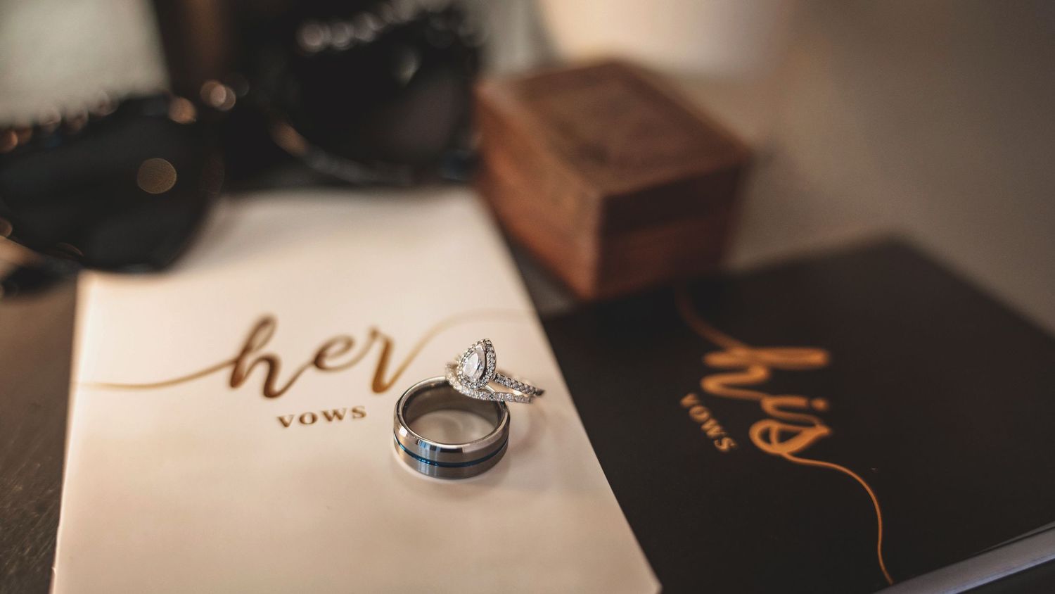 Wedding details including rings and decorative text on a table at an indoor reception.