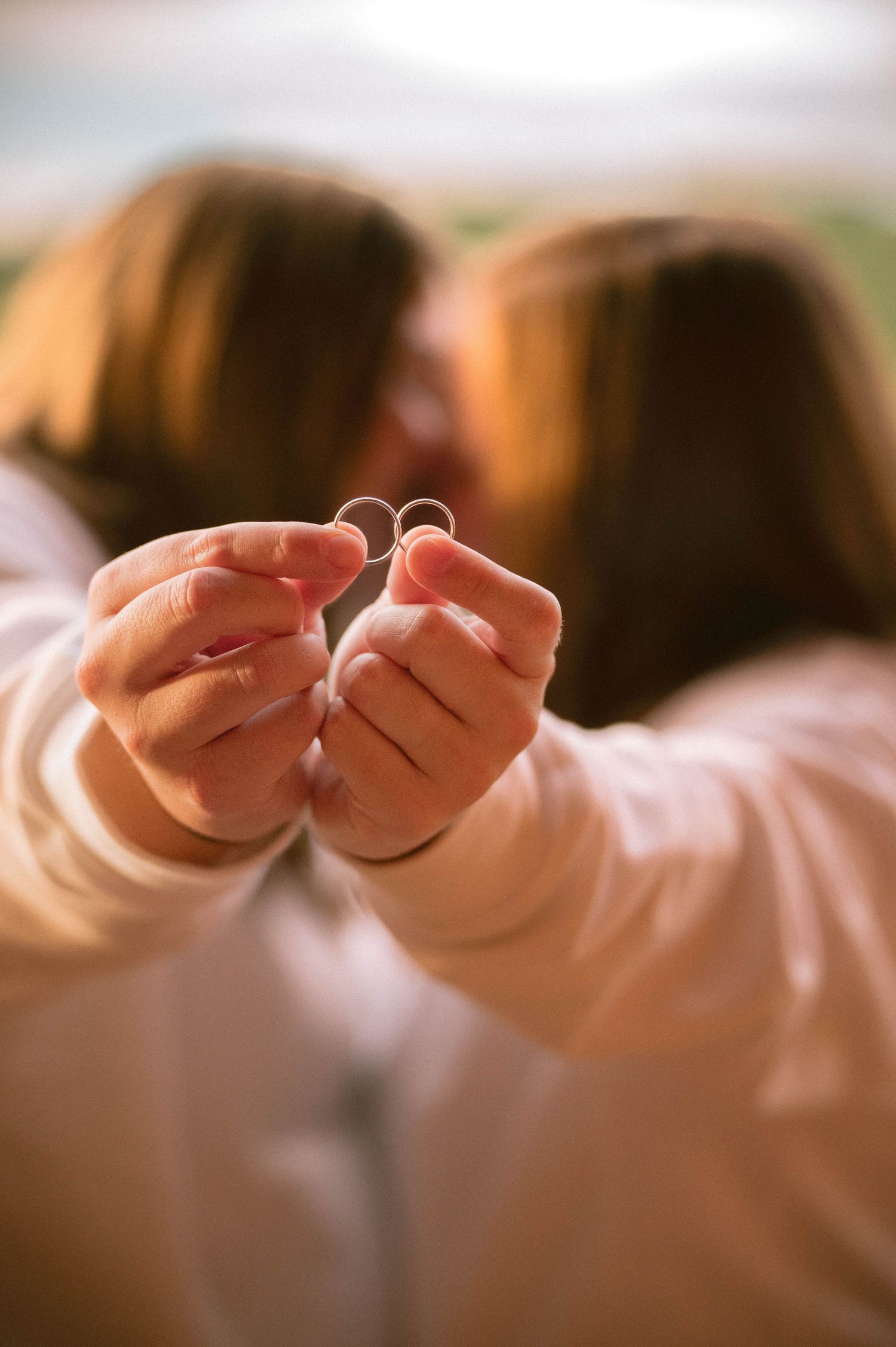 Close-up sequence of hands displaying wedding bands and engagement rings against a soft blurred background.