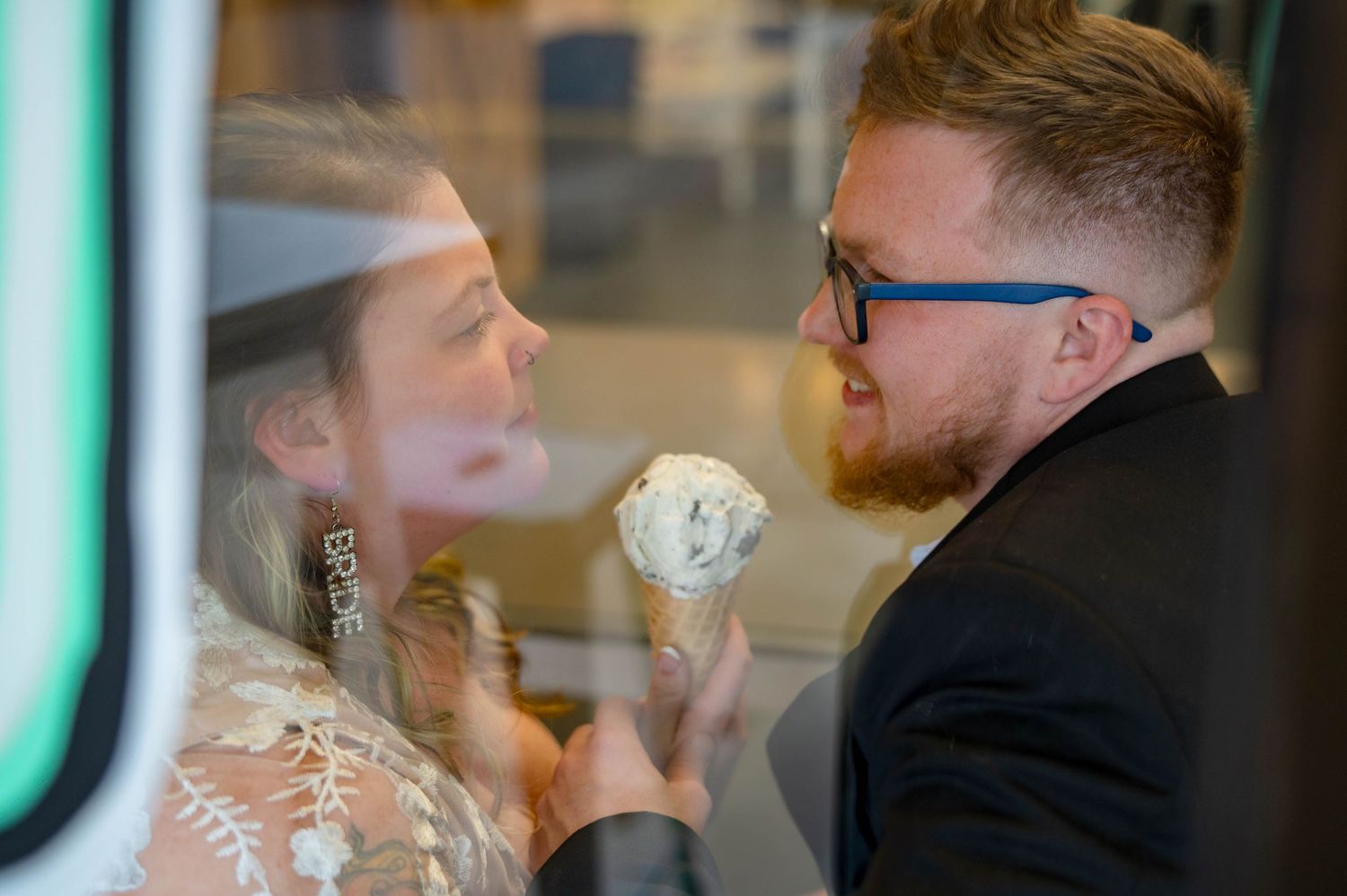 Couple enjoying ice cream together through reflective glass window.