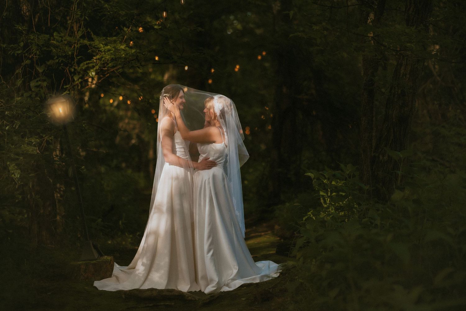A dreamy outdoor forest wedding photoshoot with a couple in white wedding attire surrounded by misty trees and warm light.