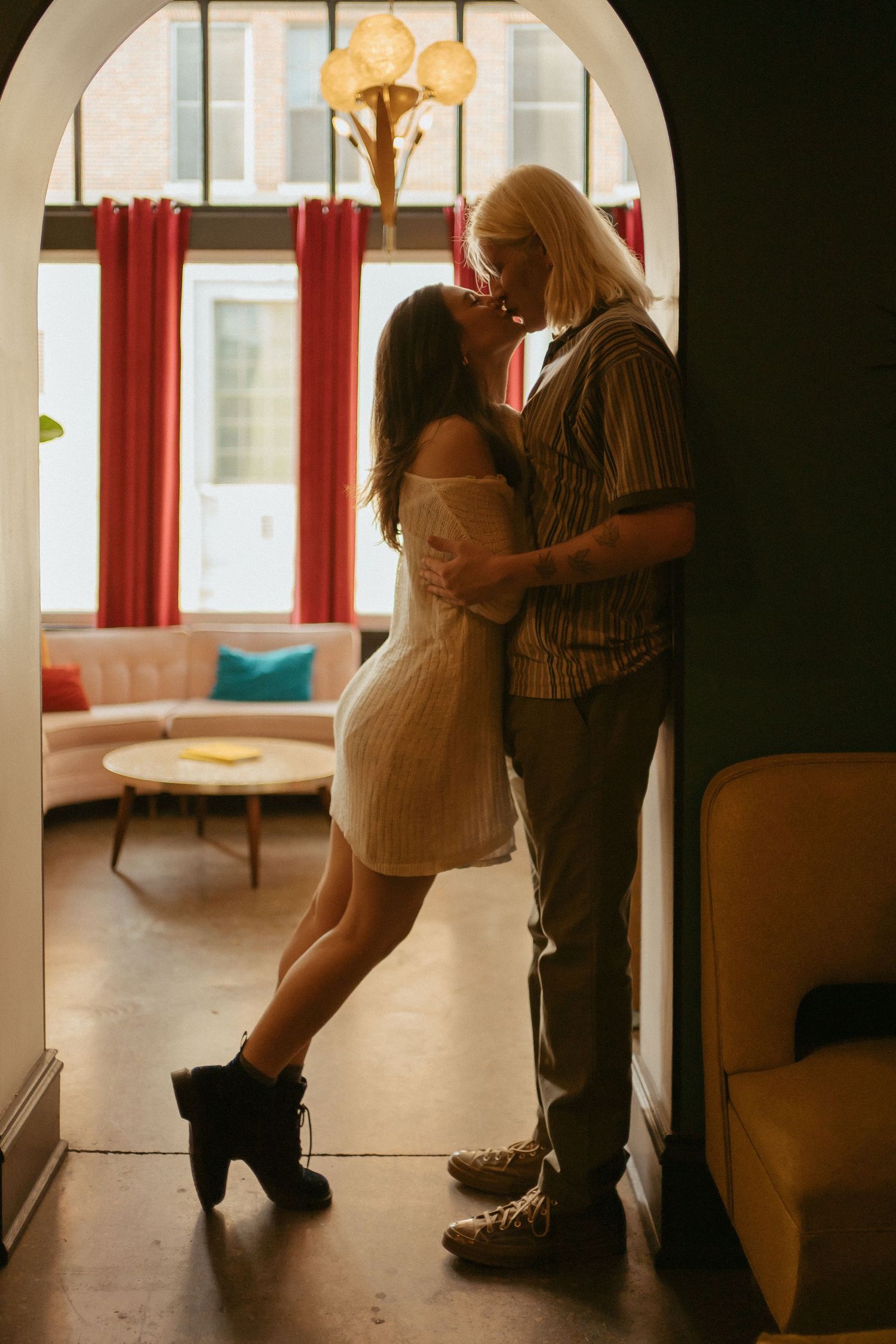Romantic couple spends intimate moments in a warmly lit indoor archway setting.