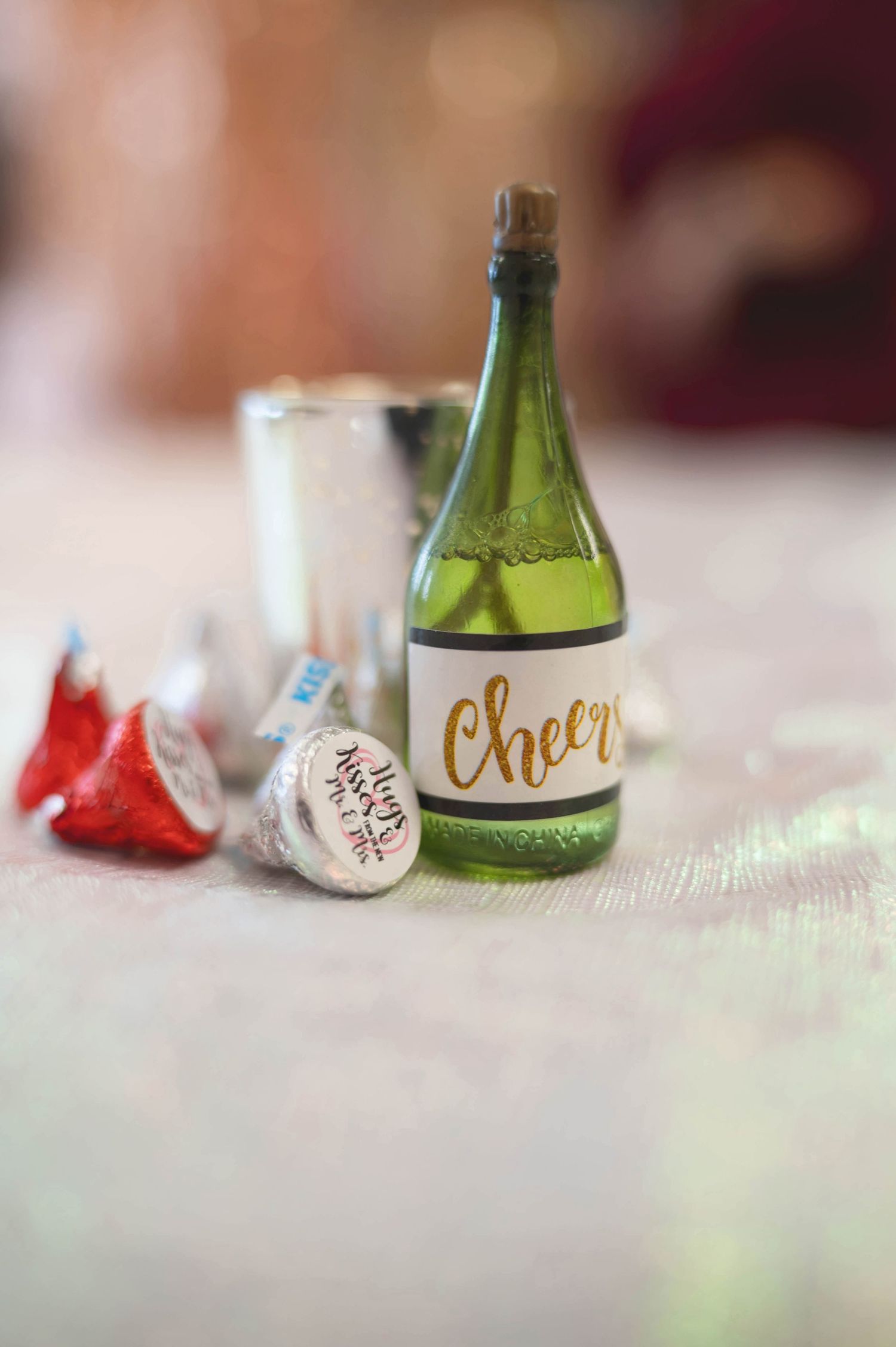 A miniature decorative green glass bottle labeled 'cheers' next to party favors.