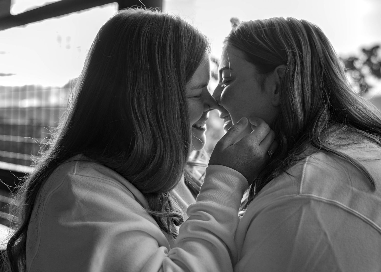 A tender intimate moment in black and white of two people embracing while sharing a close moment outdoors.