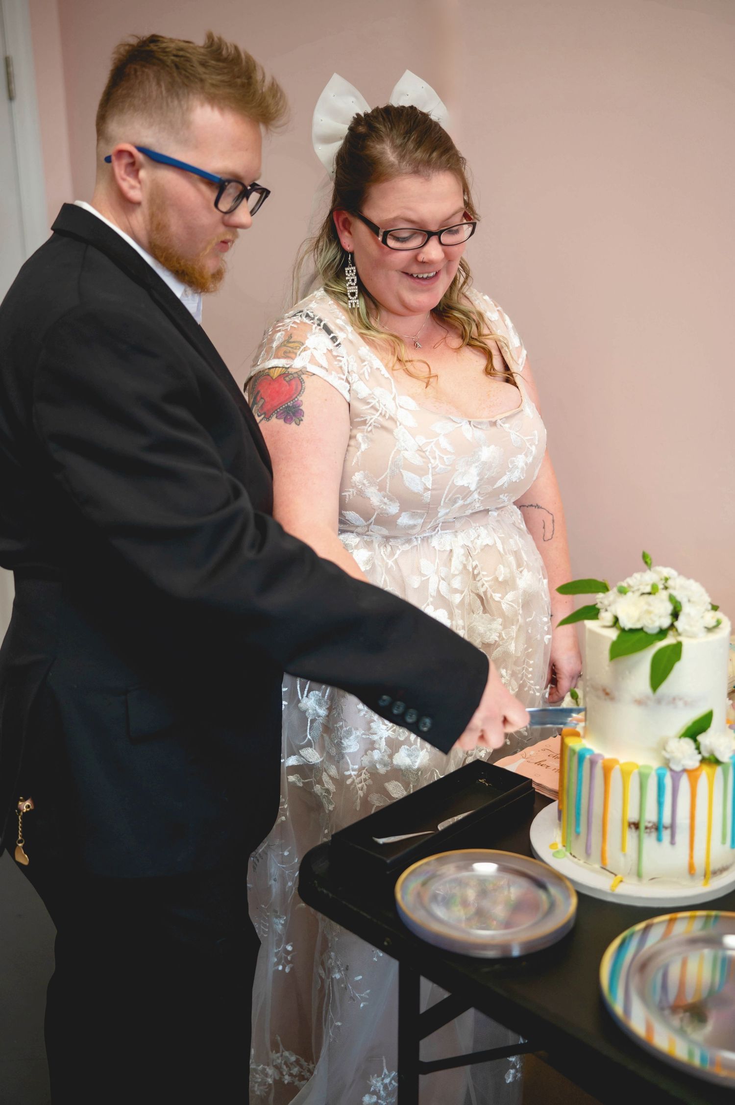 Couple cuts their wedding cake together, featuring a modern striped design with pastel colors.