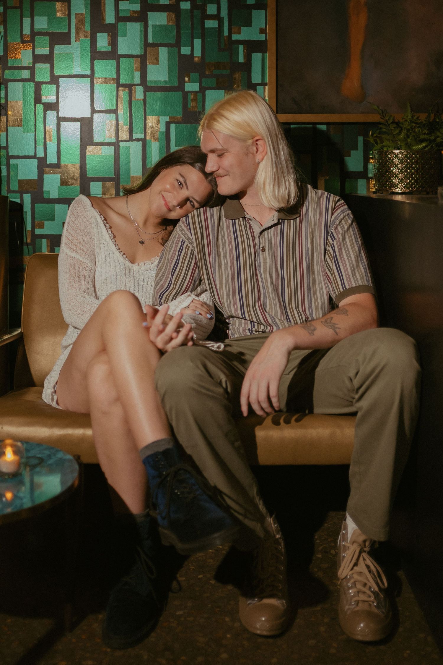 An intimate sequence of couple silhouettes sitting together against a turquoise mosaic wall in dim lighting.