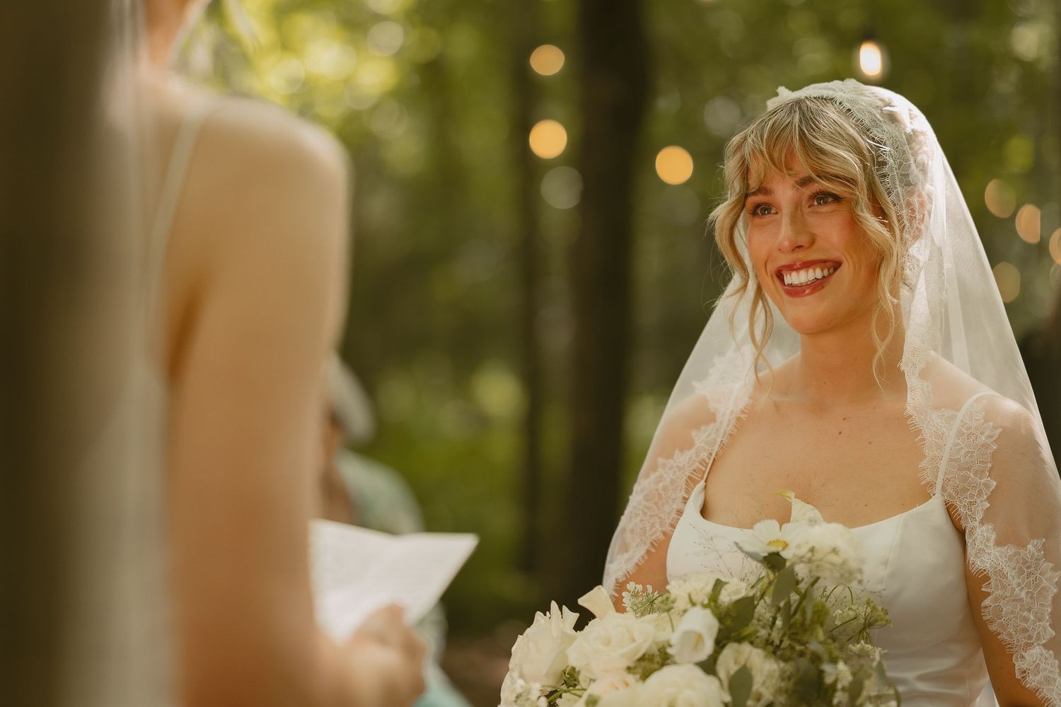 Wedding party gathering outdoors with golden sunlight filtering through trees in background.