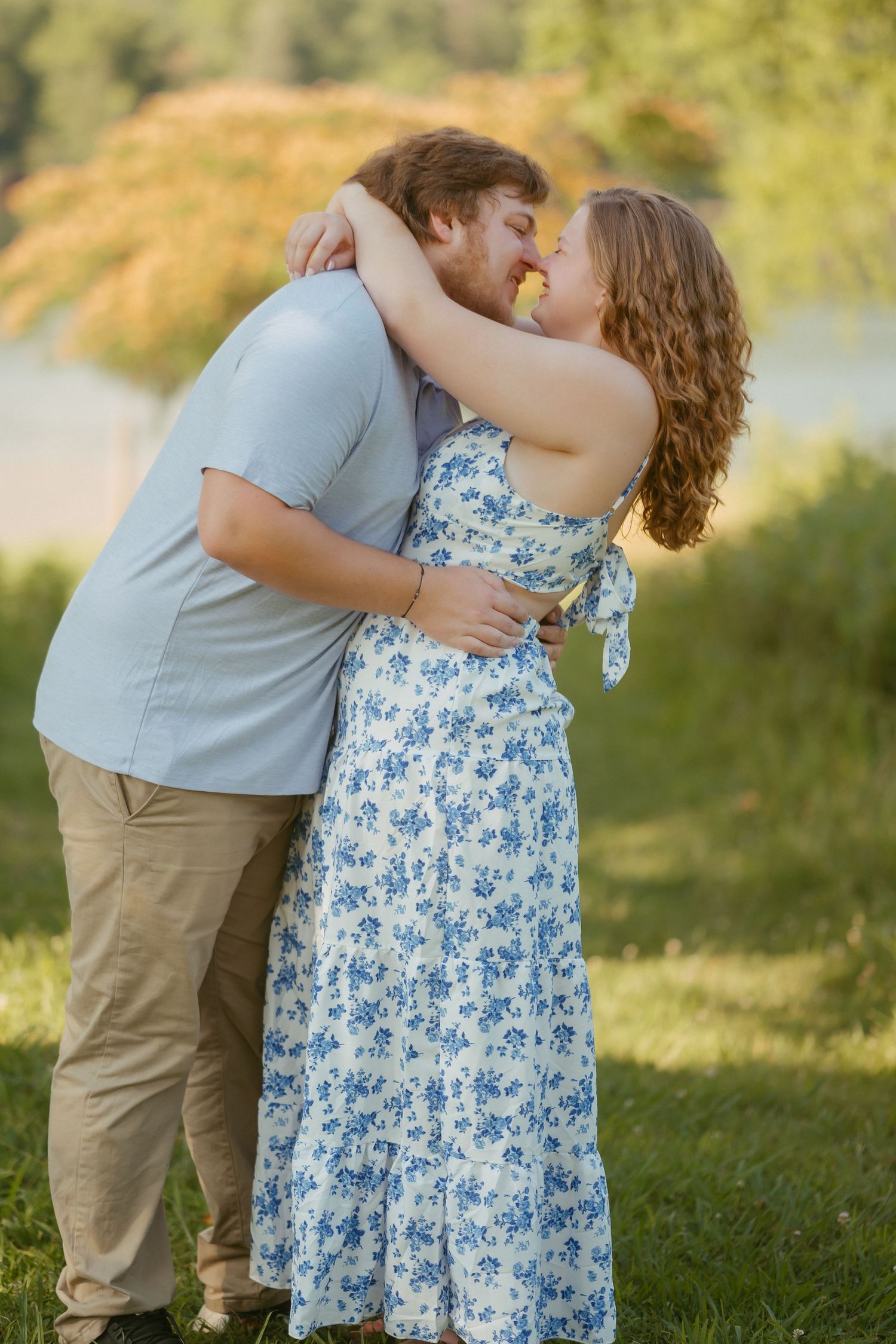 A couple in a blue dress and gray shirt embrace outdoors in a romantic photo sequence against a nature background.