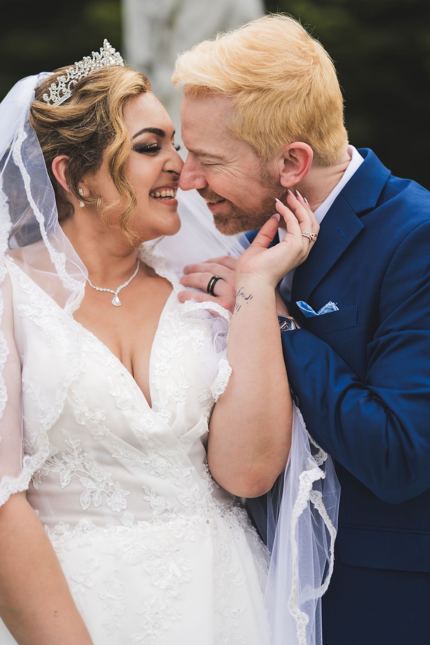 Close-up of a bride and groom's tender wedding moments with delicate lace veil and navy suit details.