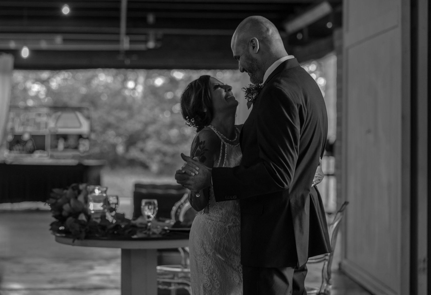 A romantic black and white moment between a couple dancing at an elegant indoor venue with ambient lighting.