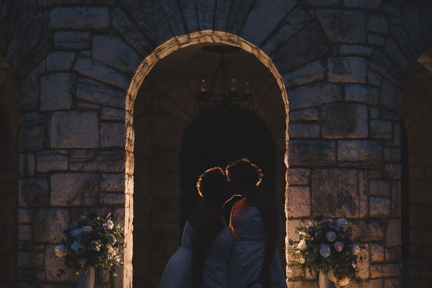 Stone arches and walkways in a Mediterranean style courtyard illuminated by warm evening light.