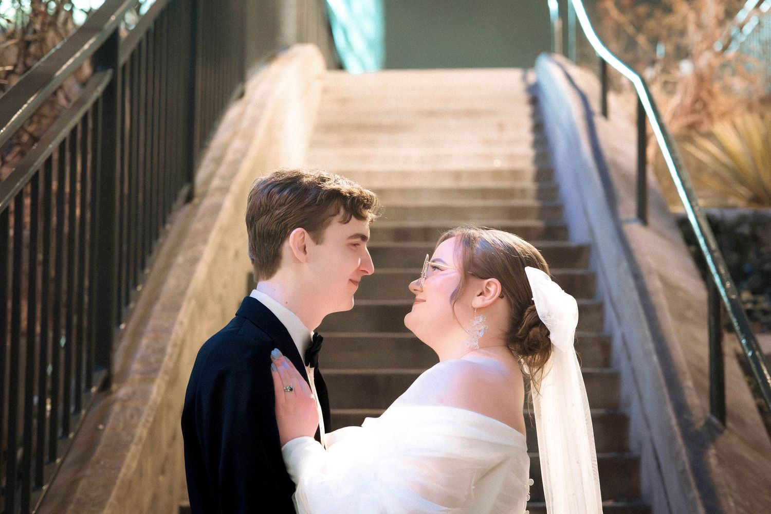 A bride and groom share a joyful moment together on a staircase during their wedding day.