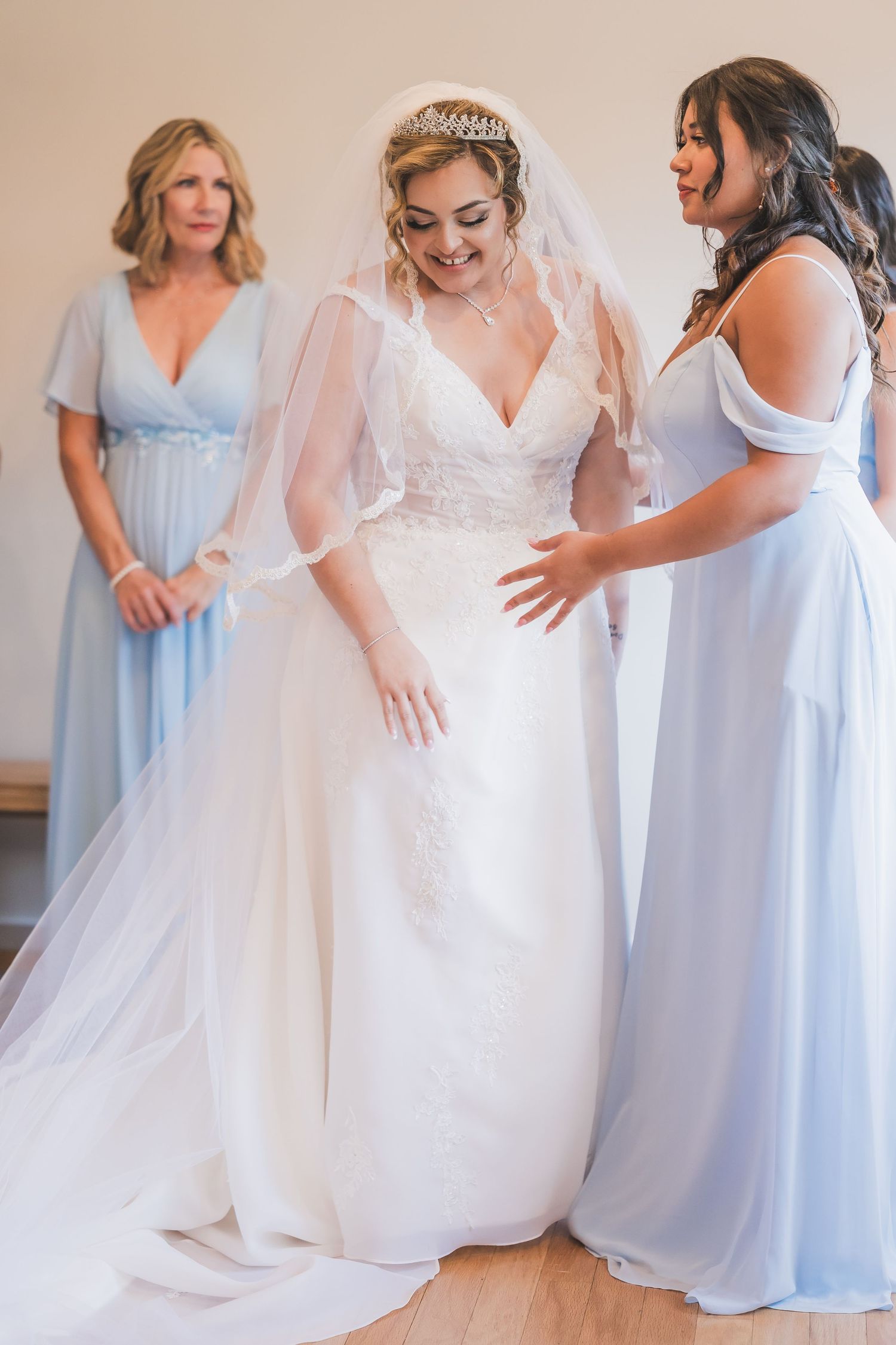 Wedding party wearing light blue bridesmaid dresses gathered around bride in flowing white gown.