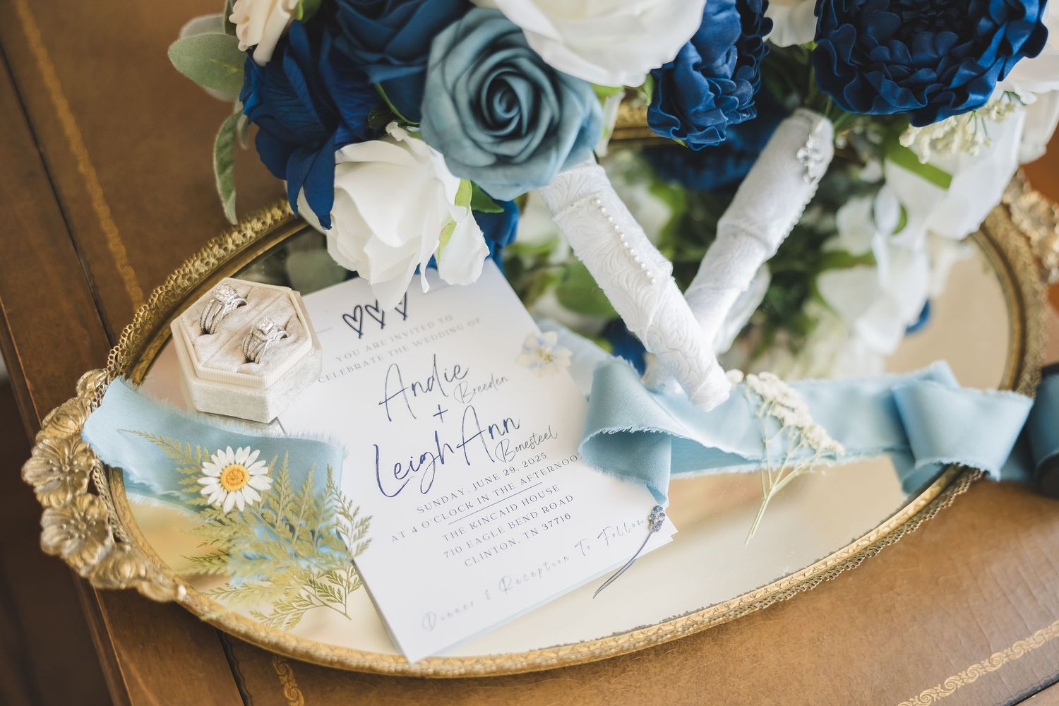 Elegant blue and white floral wedding decor arrangements displayed on silver trays with paper details and ribbons.