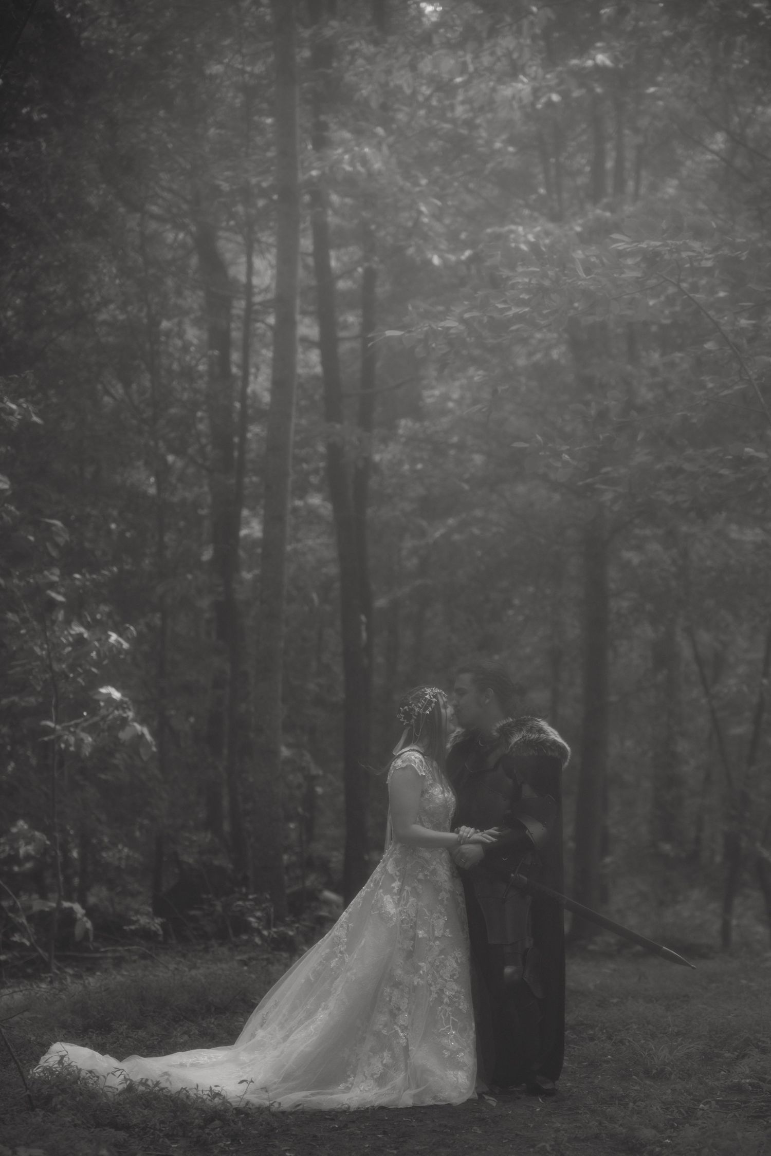 A moody black and white wedding photograph showing a flowing dress in a misty forest setting.