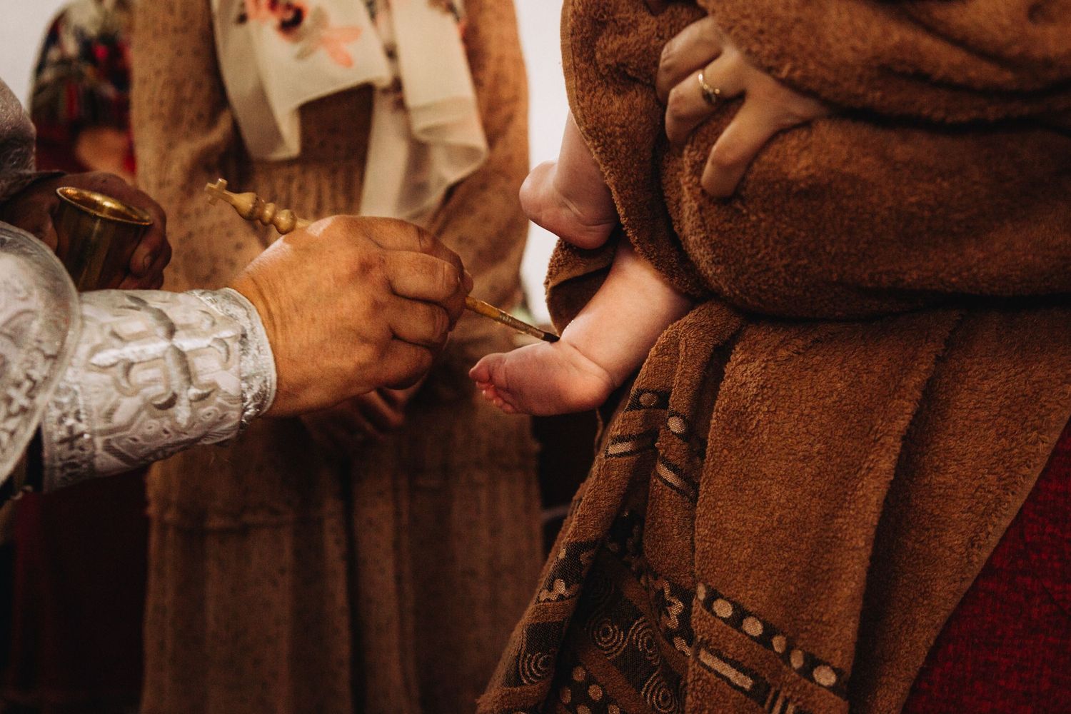 Close-up of hands during traditional religious ceremony showing embroidered vestments.