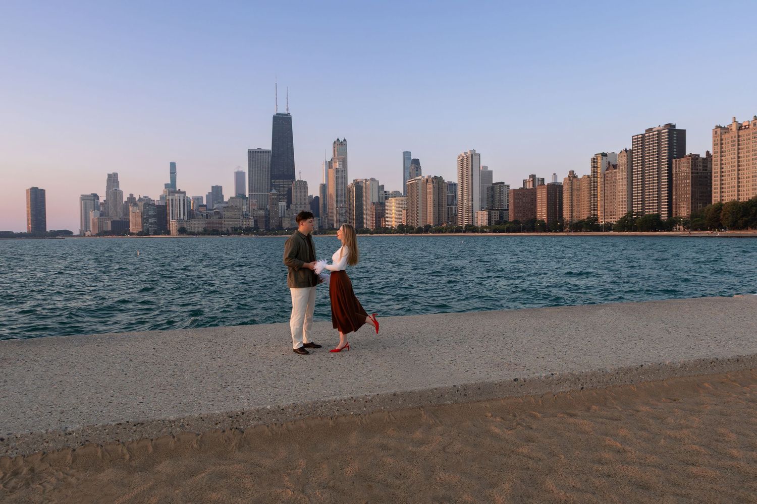 Chicago skyline and Lake Michigan shoreline viewed from North Avenue Beach during sunset.
