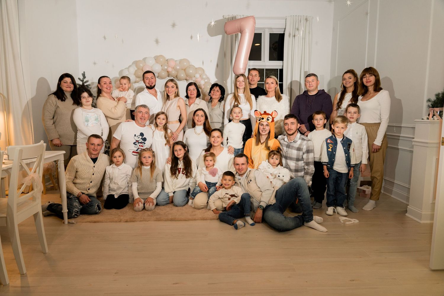 Large group photo of celebrants gathered for a special occasion under decorative balloons.