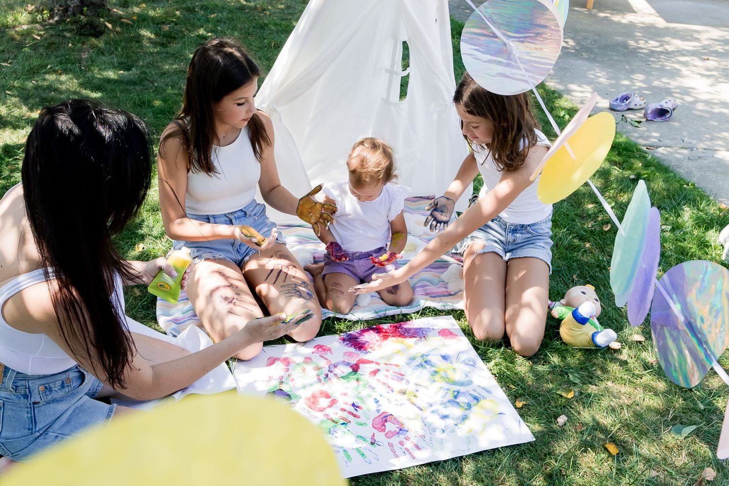 Group gathering around artwork on grass with pastel decorations hanging overhead.