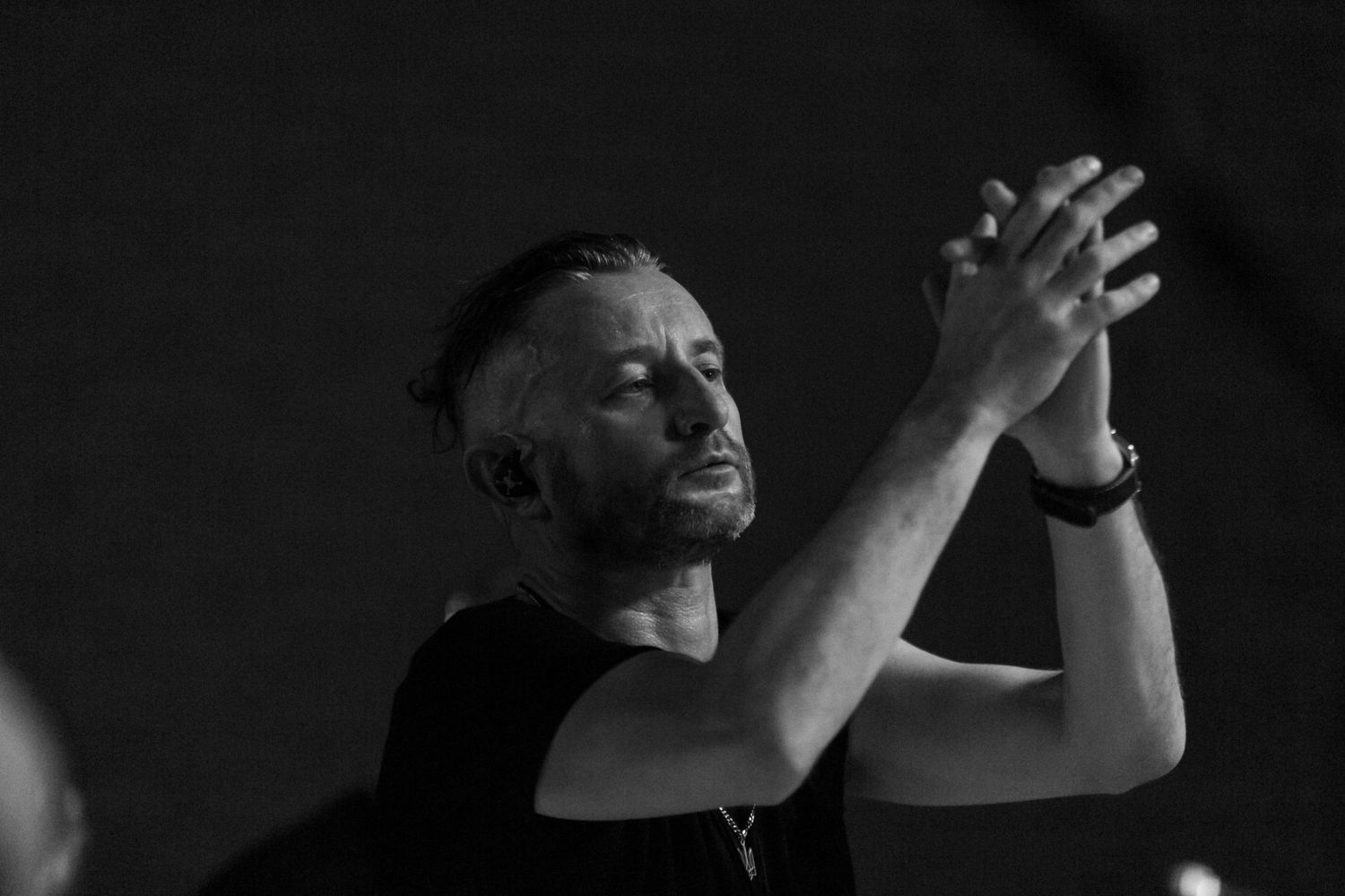Dramatic black and white shot of performer with raised hands during emotional concert moment.