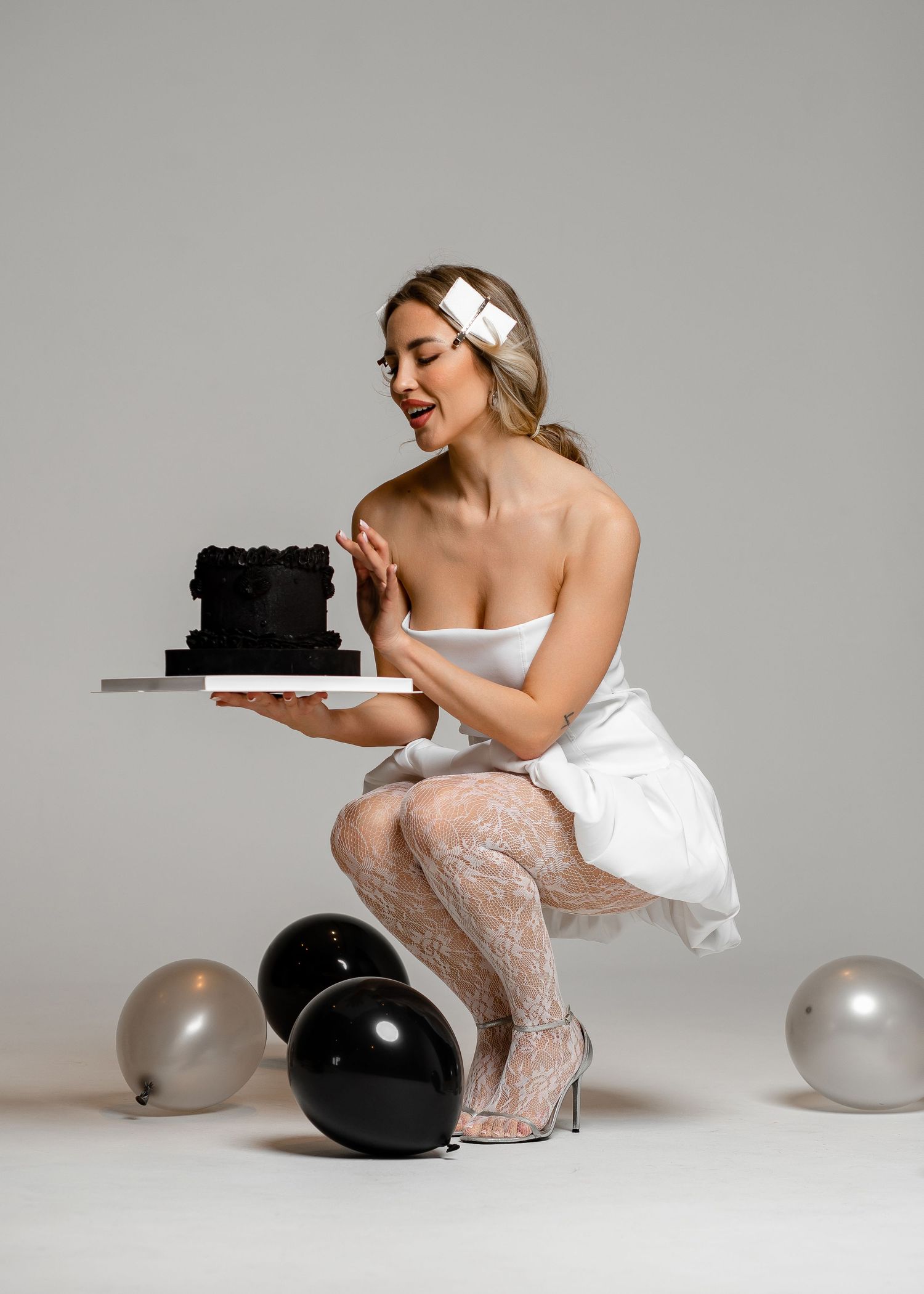 A person in a white dress and lace stockings sits on the floor with balloons and dark objects in a dramatic pose sequence.